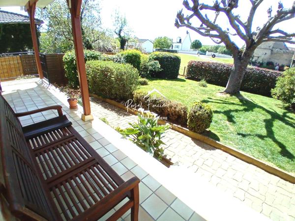 Vue sur la terrasse sous le préau et le jardin
