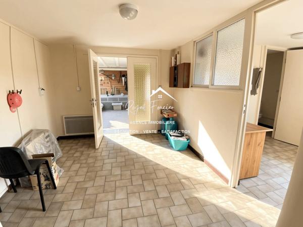 Vue sur la terrasse sous le préau et le jardin