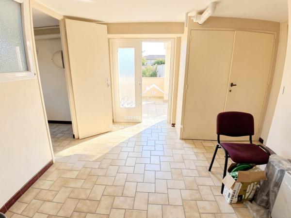 Vue sur la terrasse sous le préau et le jardin