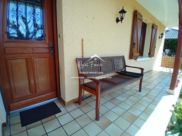 Vue sur la terrasse sous le préau et le jardin