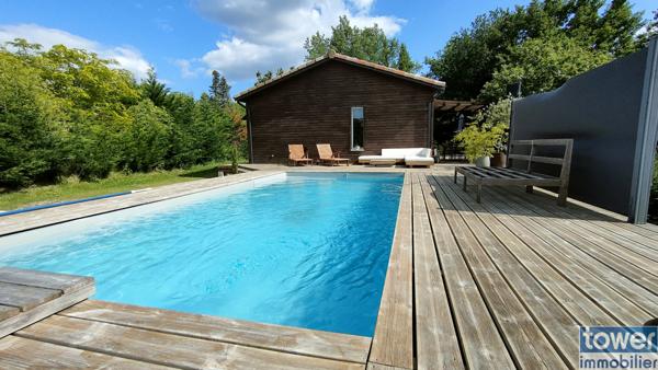 Maison en bois avec jardin et piscine.