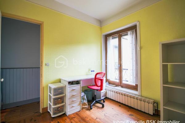 Venez découvrir cette maison atypique des années 1900 d’environ 105 m², édifiée sur une parcelle d’environ 430 m².

La maison vous accueille par une entrée ouverte sur une salle à manger, un salon avec cheminée fonctionnelle ainsi qu’une cuisine donnant directement accès au jardin situé à l’arrière de la maison.

Dès que l’on arrive sur la terrasse, l’atmosphère change complètement. Le jardin arboré, la verdure omniprésente et le calme qui s’en dégage donnent une véritable sensation de déconnexion. Un lieu agréable à vivre où l’on imagine facilement les repas d’été, les moments en famille ou simplement profiter du silence et de la nature.

À l’étage, la maison dispose de 3 chambres ainsi que d’une salle d’eau avec WC intégré. Les combles aménagés offrent également un bel espace complémentaire idéal pour un bureau, une salle TV ou une chambre d’appoint.

Un garage fermé ainsi qu’une cave complètent ce bien de caractère. Maison mitoyenne située à proximité des commerces, écoles et lignes de bus (1511, 1512 et 1517), à seulement 10 minutes du centre-ville.

Une maison avec une véritable âme, idéale pour les acquéreurs recherchant avant tout un cadre de vie paisible et chaleureux.