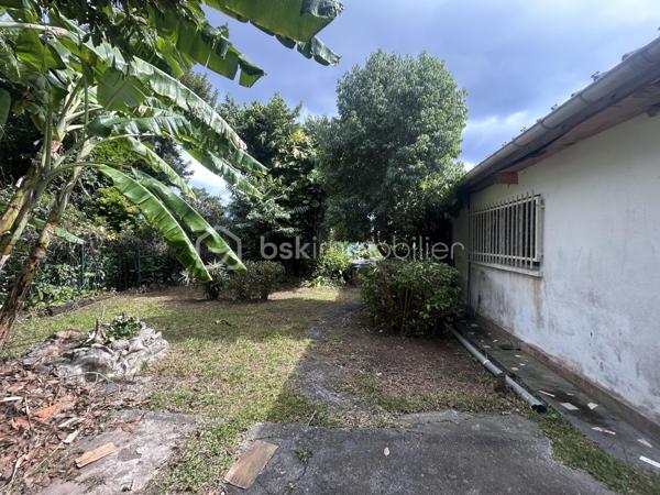 Située au 8ᵉ à La Montagne, dans un quartier résidentiel calme, cette maison à rénover de 161 m² habitables est implantée sur une parcelle de 914 m² arborée, à proximité immédiate du village, des commerces (supermarché, boulangerie, pharmacie), des écoles et des principaux axes.

La maison se compose, au rez-de-chaussée, d’un séjour de 28 m² offrant un bel espace de vie ainsi que de trois grandes chambres aux volumes confortables. Son agencement permet d’envisager différents projets de rénovation et d’aménagement selon vos besoins.

À l’extérieur, une varangue de 28 m² prolonge les espaces de vie et donne sur un terrain planté de letchis, de canneliers et d’ylang-ylang. Une allée permet de stationner plusieurs véhicules sur la propriété.

Le bien est équipé d’un chauffe-eau solaire et l’assainissement est assuré par une fosse septique.

Le montant de la taxe foncière est de 2400€.

Cette maison constitue une belle opportunité pour les acquéreurs souhaitant rénover un bien spacieux, bénéficiant d’un grand terrain et d’un emplacement recherché à La Montagne.