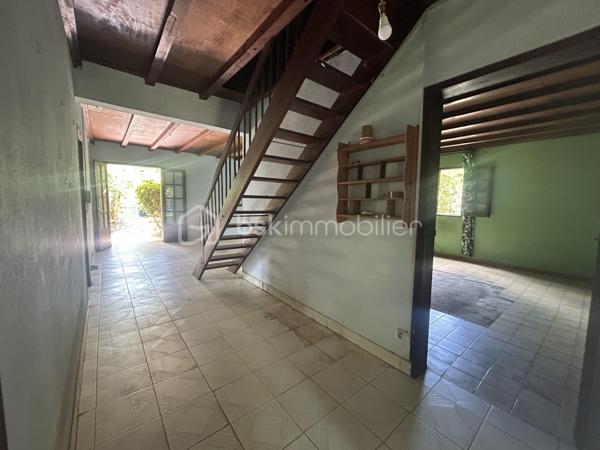 Située au 8ᵉ à La Montagne, dans un quartier résidentiel calme, cette maison à rénover de 161 m² habitables est implantée sur une parcelle de 914 m² arborée, à proximité immédiate du village, des commerces (supermarché, boulangerie, pharmacie), des écoles et des principaux axes.

La maison se compose, au rez-de-chaussée, d’un séjour de 28 m² offrant un bel espace de vie ainsi que de trois grandes chambres aux volumes confortables. Son agencement permet d’envisager différents projets de rénovation et d’aménagement selon vos besoins.

À l’extérieur, une varangue de 28 m² prolonge les espaces de vie et donne sur un terrain planté de letchis, de canneliers et d’ylang-ylang. Une allée permet de stationner plusieurs véhicules sur la propriété.

Le bien est équipé d’un chauffe-eau solaire et l’assainissement est assuré par une fosse septique.

Le montant de la taxe foncière est de 2400€.

Cette maison constitue une belle opportunité pour les acquéreurs souhaitant rénover un bien spacieux, bénéficiant d’un grand terrain et d’un emplacement recherché à La Montagne.