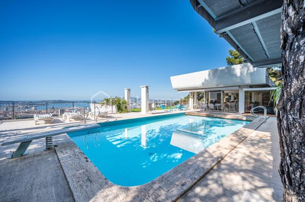 TOULON – FARON | Appartement-villa d’exception avec panorama sur la mer et la rade

Sur les hauteurs du Faron, au sein d’une copropriété de standing à l’architecture remarquable, ce bien rare occupe le dernier niveau et bénéficie d’un cadre de vie privilégié, entre mer, nature et élégance.

Véritable appartement-villa développé de plain-pied, il offre plus de 200 m² habitables sur un ensemble d’environ 1 000 m², en jouissance exclusive. Il conjugue le confort d’un appartement avec l’esprit d’une villa : volumes généreux, circulation fluide sur un seul niveau, accès privatif, extérieurs d’exception et piscine privative.

Dès l’entrée, le regard se laisse naturellement porter vers la Méditerranée. La mer, la rade de Toulon et les reliefs environnants dessinent un décor d’une rare intensité, visible depuis les espaces de réception comme depuis les extérieurs. Ici, le panorama ne se contemple pas seulement : il devient une composante essentielle de l’art de vivre offert par ce lieu unique.

Pensé autour d’un véritable art de vivre indoor-outdoor, ce bien offre une continuité rare entre intérieur et extérieur. Les espaces de réception se prolongent naturellement vers les terrasses, créant une atmosphère lumineuse, ouverte et entièrement tournée vers le panorama.

La pièce de vie, d’une superficie de plus de 75 m², constitue le cœur du bien. Ses belles proportions, sa cheminée et son ouverture direct à l’extérieur en font un espace à la fois élégant, chaleureux et convivial. La cuisine équipée s’inscrit dans le même esprit de confort et de raffinement.

L’espace nuit comprend trois chambres, dont une suite parentale avec salle de bains privative, ainsi qu’une seconde salle de bains et un bureau pouvant être aménagé en quatrième chambre. La distribution préserve l’intimité des espaces privés tout en conservant une circulation harmonieuse.

À l’extérieur, terrasses, jardin, piscine de 5 x 11 mètres, une cuisine d’été avec sanitaire, et une terrasse couverte. Ces espaces prolongent l’appartement comme une véritables pièces de vie à ciel ouvert, idéales pour recevoir, se détendre et de profiter pleinement du climat méditerranéen dans un cadre privilégié face à la mer et à l’une des plus belles rades du monde.

Un accès privatif, plusieurs emplacements de stationnement et deux caves complètent cet ensemble rare sur le marché toulonnais.

Ce bien réunit les atouts d’un appartement de standing — sécurité, dernier étage, vie de plain-pied — et le confort d’une villa, avec ses extérieurs généreux, sa piscine privative, son adresse confidentielle et l’absence de vis-à-vis.

Un bien unique sur le secteur du Faron, destiné à une clientèle recherchant un lieu de vie rare, élégant et résolument tourné vers l’art de vivre méditerranéen.

Des prestations soignées et haut de gamme complètent ce bien d’exception, avec chauffage individuel au gaz, climatisation réversible et système d’arrosage automatique, pour un confort optimal en toute saison.