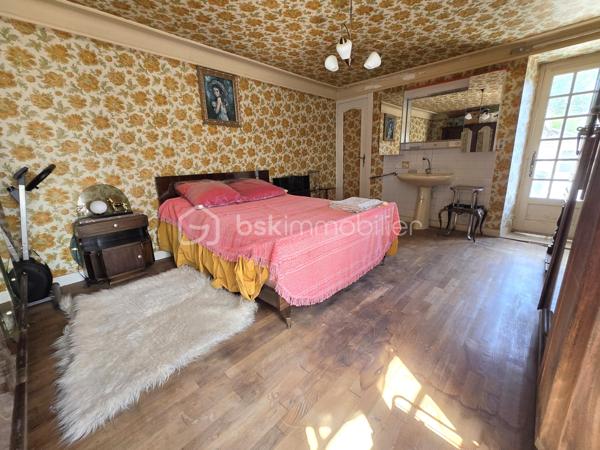 Au cœur du bourg, cette maison en pierre mitoyenne d’un côté offre une belle surface habitable, de nombreux espaces et un potentiel intéressant pour qui souhaite lui redonner une nouvelle vie.
Le rez-de-chaussée s’organise autour d’une entrée desservant une cuisine, une salle à manger, un salon, ainsi qu’une chambre avec point d’eau. Un dégagement mène également à un WC indépendant avec lavabo.
À l’étage, le palier dessert quatre chambres, une salle de bains, une salle d’eau et un second WC indépendant. Au-dessus, un grenier d’environ 35 m² vient compléter l’ensemble et offre une possibilité supplémentaire d’aménagement.
La maison a conservé son intérieur d’origine et nécessite aujourd’hui une rénovation et une remise au goût du jour, notamment pour la cuisine, les pièces d’eau, l’électricité et l’isolation. Le chauffage central au fioul est actuellement fonctionnel et l’installation dessert l’ensemble de la maison. 
À l’extérieur, les dépendances apportent un véritable atout avec une grange d’environ 65 m², une cave de 11,35 m², ainsi qu’un garage d’environ 30 m². Un cabanon, une terrasse et un jardin complètent la propriété, le tout sur un terrain d’environ 796 m².
Une maison qui offre avant tout une belle base et un véritable potentiel de transformation : les volumes sont là, les dépendances aussi, et les futurs propriétaires pourront progressivement la réinventer pour créer un intérieur à leur image.
Un bien à découvrir pour celles et ceux qui recherchent le charme de la pierre, de l’espace et un projet de rénovation à personnaliser.