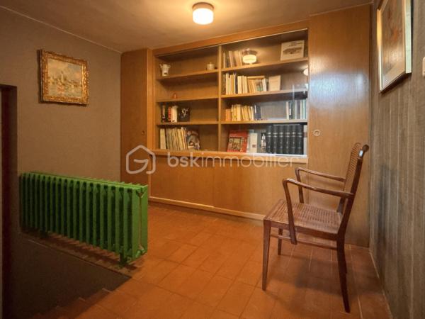 bonjour. Voici l'essentiel : 
à Gières au fort du Mûrier, une villa-belvédère 
258 m2 habitables 
158 m2 locaux annexes
416 m2 surface utile
6 chambres
4 salles de bain
Piscine à débordement
Terrain arboré et clos : 6737 m2 (chemin de ronde partiellement)

Bienvenue à celles et ceux qui préfère emprunter le « chemin de ronde » architectural :
A l'aube des années 80, aucune entrave à l'audace de ces jeunes architectes et commanditaires qui saisissent cette exceptionnelle opportunité de construire cette villa-belvédère au flanc du Fort du Mûrier à Gières qui verrouille la vallée du Grésivaudan.
La villa lui emprunte sa matérialité, son ancrage et sa compacité qu'elle exprime par les outils architecturaux développés dans le sillage de Le Corbusier.
Là où le Fort retourne comme un gant l'alignement des façades de ses casemates en une rue utilitaire  encastrée, la villa, sous le ruban de la haute poutre-acrotère du toit-terrasse, déploie, par redents irréguliers, l'alternance de ses parois pleines et vitrées toute hauteur.
Elle exalte la minéralité de sa périphérie de terrasses gravillonnées, d'une brique nuancée appareillée horizontalement en pans ourlés et d'un béton aux épidermes multiples tantôt lisse, tantôt brut de décoffrage, parfois avec méplats mais toujours d'expression verticale et favorise sa vocation résidentielle par les nombreux et généreux pans vitrés de son rez-de-jardin de 222 m2 intégralement de plain-pied. 
A cette projection dans le paysage proche et lointain répond une fluidité intérieure autorisée par la prédilection des échappées visuelles obliques et un certain dépouillement général.
Au final,  sans en imposer mais avec fermeté, sans mimétisme au fort, par son inaltérable minimalisme, la villa-belvédère semble surgie hier autant que depuis des temps immémoriaux.

Une chambre d'écho aux bruissements des éléments, du végétal et de la montagne.
Comme le fort organise sa vie défensive en fonction de sa rue en boomerang, la villa répartit son organisation de part et d'autre d'une rue intérieure dotée de la même orientation nord-ouest/sud-est salutaire eu égard au réchauffement climatique. 
Au nord, l’espace nuit de hauteur conventionnelle comprend 4 chambres, 3 salles d’eau nimbées d'une subtile lumière zénithale et 2 wc. Toutes les chambres s'exonèrent d'une vue frontale sur le fort au profit d'orientations est et ouest plus agréables. La suite parentale outre le privilège de ses 27 m2 et sa baie cadrant les trois pics de Freydone, dispose d'un accès doublé par le salon surélevé. Arrêtons-nous sur cette pièce singulière qui jouit d'un rapport visuel immédiat avec le miroir d'eau sur lequel flotte la chaine de Belledonne...salon tour-à-tour empli de la rumeur ludique de la piscine et assurément contemplative la nuit ou aux aurores, sa triple ouverture et son surplomb du hall l'apparentent au campement à la « croisée des chemins »  ce dont atteste la ligne fuyant et sinueuse des ganivelles de châtaigner du chemin de ronde.

Au sud de la rue intérieure, avec laquelle ils partagent une hauteur sous plafond avoisinant les 3 mètres, se déploient les lieux de rassemblement ou de concentration que sont le séjour, la cuisine, la salle-à-manger et le bureau.
Le séjour en contrebas de la rue intérieure s'organise autour du bloc massif intégrant le foyer-insert et son alter-ego le barbecue de la terrasse couverte des repas de mi-saison et d'été. Son plafond de panneaux de chêne massif confère à la pièce une couleur acoustique propice aux confidences.
On peut qualifier la cuisine d'agora familiale tant son organisation centripète permet de s'y tenir bien au-delà de sa fonction première de préparation des repas. Sa table tout en transparence dissout la frontière entre cuisine et terrasse tandis que ses ouvertures cardinales en diagonale permettent un contrôle visuel de toute la propriété : l'arrivée des visiteurs, le chevreuil du chemin de ronde, le gazouillis des oiseaux proches. Et que dire de son mobilier minimaliste et inaltérable aux couleurs hédoniques qui répond à sa mission depuis un demi-siècle avec la même justesse ?
Le niveau bas -d'égale surface- est purement fonctionnel. Au nord-ouest et de plain-pied avec l'accès à la propriété, le vaste garage est accessible par 3 portes sectionnelles et donne accès à un studio. Du fait de l'encastrement dans la déclivité du terrain et donc totalement enterrés, vous trouvez les espaces techniques tels que -principalement- la filtration de la piscine à débordement, la chaufferie et sa chaudière Weishaupt, la conserverie-cave à vins, la buanderie, l'atelier. Les vides sanitaires hauteur d'homme et partiellement soustrait à la roche réservent des opportunités d'aménagement. 

La villa s'implante au sud de l'équerre formé par le chemin de ronde et en lisière du hameau -solitaire mais solidaire- dont elle se protège par un écran végétal et une certaine déclivité.
Prolongement naturel du demi-kilomètre que constitue le tour de la propriété, un escalier extérieur donne accès au toit-terrasse qui offre une vue panoramique à 360 degrés sur le Vercors, Grenoble, la dent de Crolles, le Grésivaudan, le Mont-blanc par beau temps et la chaine de Belledonne. 
La boucle du Fort du Mûrier passe au pied de la propriété et offre au cours de ses deux heures de marche une succession de panoramas, selon les randonneurs, « à coupe le souffle ».
Aux portes de Grenoble, Gières, bien desservie par la rocade nord-est et à la croisée de plusieurs domaines skiables rejoints en moins d'une demie-heure, elle est dotée de tous les commerces et services. Mais une telle adresse se mérite et il faut - depuis le bourg - gravir un dénivelé de plus de 200 mètres pour atteindre le Fort et la villa.

Alain CHIAUDANO & Régis HERBIN, l’héroïque binôme architectural 
Durant les deux années précédant la construction, les commanditaires ont affronté de nombreuses résistances à leur projet mais cela n'a entamé en rien ni leur envie de vivre en ce lieu solitaire et grandiose ni la conviction d'Alain Chiaudano d'un plateau de vie -« bunker » en lévitation- affranchi de toute enveloppe conventionnelle. Malheureusement, quelques mois avant l'ouverture du chantier, l'architecte est emporté par la maladie et c'est son ami et associé régis Herbin qui fera preuve d'abnégation et de respect mémoriel. Porté par l'encouragement sans faille des commanditaires, le jeune architecte livrera en 15 mois une œuvre unique où tout est calepiné, apparent, doté d'une science des rythmes, des épidermes et de l'espace qui n'est pas sans rappeler l'Atelier de Montrouge de la première heure ou le binôme Le Corbusier-Wogenscky. 
Les améliorations que les résidents lui ont prodigué au fil des ans, la belle patine des ouvrages et au final, l'absence de toute modification majeure témoignent de la pertinence des choix initiaux et attestent de son état impeccable.