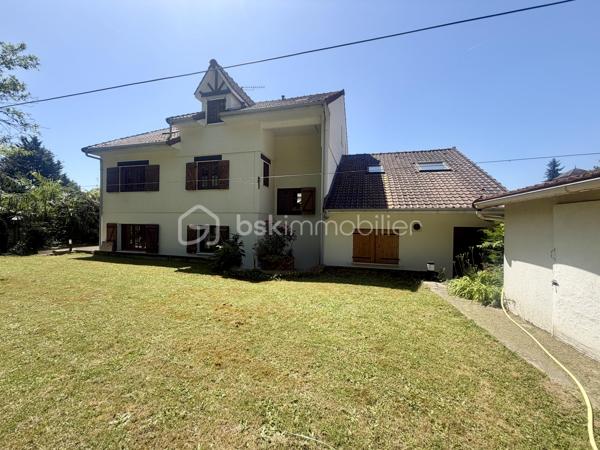 Nous vous proposons en exclusivité cette remarquable maison familiale atypique et polyvalente, offrant des volumes généreux et de nombreuses possibilités d’aménagement, idéalement implantée sur un terrain arboré de plus de 1 000 m².

🏡 Espace principal (accès par escaliers) :
Le cœur de la maison s’articule autour d’un séjour double lumineux ouvrant sur un balcon, agrémenté d’un poêle à bois pour une ambiance chaleureuse. La cuisine ouverte entièrement aménagée et équipée, prolongée par un cellier, en fait un espace de vie idéal pour recevoir en famille. Cet étage comprend également une suite parentale ainsi qu’une grande pièce modulable pouvant servir de bureau ou de chambre supplémentaire.

🛏️ Étage supérieur :
Quatre chambres dont deux avec placards intégrés, et une salle de bains avec WC semi-indépendant complètent cet espace nuit généreux et fonctionnel.

🔑 Rez-de-chaussée – Une vraie valeur ajoutée :
Le niveau inférieur offre une véranda, un placard d’entrée et un local technique. Le garage double avec deux ateliers attenants séduira les amateurs de bricolage ou les professionnels.

Point fort du bien : un appartement T2 totalement indépendant — actuellement loué 900 €/mois — composé d’un séjour, d’une cuisine, d’une chambre, d’une salle d’eau, de WC indépendants et d’un bureau aménagé avec sauna. Idéal pour un projet familial (logement d’un proche) ou pour optimiser la rentabilité locative.

🌿 Extérieur :
Le jardin dispose de deux puits et d’une réserve d’eau, ainsi que d’une dépendance divisée en trois espaces distincts à l’arrière de la propriété — offrant de multiples usages selon vos besoins.

⚙️ Prestations techniques :
Bien entretenu et régulièrement mis à jour :
	•	Tableau électrique triphasé
	•	VMC double flux
	•	Radiateurs connectés pilotables par zone
	•	Ballon thermodynamique de 300 L (remplacé en 2019)
	•	Fibre optique
	•	Dalles béton au RDC et R+1 — ossature bois au R+2

Votre conseillère est disponible 7j/7.
📞 Contactez-nous dès maintenant pour programmer votre visite.