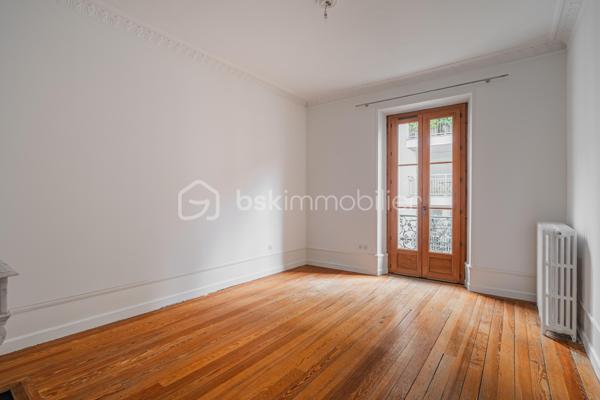 À quelques pas du centre-ville d’Aix-les-Bains et de la gare, dans un environnement recherché pour son calme et sa qualité de vie, découvrez ce superbe appartement haussmannien rénové de 82 m² situé au 1er étage d’un élégant immeuble bourgeois.

Dès l’entrée, le charme opère immédiatement. Parquet bois, moulures d’époque, belle hauteur sous plafond et volumes généreux confèrent à l’appartement une atmosphère chaleureuse et raffinée, idéale pour les amateurs de biens de caractère.
La pièce de vie, baignée de lumière grâce à son exposition Ouest, offre un espace convivial et élégant où la cuisine équipée s’intègre parfaitement grâce à une magnifique verrière atelier, apportant une touche contemporaine au cachet de l’ancien.

L’appartement propose deux chambres spacieuses et confortables, parfaites pour un couple, une petite famille ou un espace bureau pour le télétravail. Une salle de bains avec baignoire ainsi qu’un WC.

Deux balcons viennent renforcer le caractère rare et authentique du bien, tandis qu’une cave et un grenier apportent un confort de rangement appréciable au quotidien.
Entièrement rénové, l’appartement permet de profiter immédiatement d’un cadre de vie élégant et fonctionnel. La future réfection complète de la toiture, déjà votée par la copropriété, constitue également un véritable avantage patrimonial pour les futurs propriétaires.

Vous profiterez d’un emplacement particulièrement apprécié, offrant l’équilibre parfait entre vie citadine, accessibilité et tranquillité, à proximité immédiate des commerces, transports, restaurants et commodités d’Aix-les-Bains.

Chauffage gaz collectif inclus dans les charges de copropriété.
Un appartement lumineux, élégant et plein de charme, idéal pour ceux qui recherchent un bien de caractère dans l’un des secteurs les plus agréables d’Aix-les-Bains.
