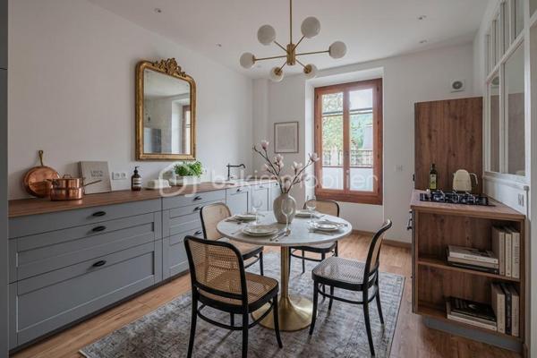 À quelques pas du centre-ville d’Aix-les-Bains et de la gare, dans un environnement recherché pour son calme et sa qualité de vie, découvrez ce superbe appartement haussmannien rénové de 82 m² situé au 1er étage d’un élégant immeuble bourgeois.

Dès l’entrée, le charme opère immédiatement. Parquet bois, moulures d’époque, belle hauteur sous plafond et volumes généreux confèrent à l’appartement une atmosphère chaleureuse et raffinée, idéale pour les amateurs de biens de caractère.
La pièce de vie, baignée de lumière grâce à son exposition Ouest, offre un espace convivial et élégant où la cuisine équipée s’intègre parfaitement grâce à une magnifique verrière atelier, apportant une touche contemporaine au cachet de l’ancien.

L’appartement propose deux chambres spacieuses et confortables, parfaites pour un couple, une petite famille ou un espace bureau pour le télétravail. Une salle de bains avec baignoire ainsi qu’un WC.

Deux balcons viennent renforcer le caractère rare et authentique du bien, tandis qu’une cave et un grenier apportent un confort de rangement appréciable au quotidien.
Entièrement rénové, l’appartement permet de profiter immédiatement d’un cadre de vie élégant et fonctionnel. La future réfection complète de la toiture, déjà votée par la copropriété, constitue également un véritable avantage patrimonial pour les futurs propriétaires.

Vous profiterez d’un emplacement particulièrement apprécié, offrant l’équilibre parfait entre vie citadine, accessibilité et tranquillité, à proximité immédiate des commerces, transports, restaurants et commodités d’Aix-les-Bains.

Chauffage gaz collectif inclus dans les charges de copropriété.
Un appartement lumineux, élégant et plein de charme, idéal pour ceux qui recherchent un bien de caractère dans l’un des secteurs les plus agréables d’Aix-les-Bains.