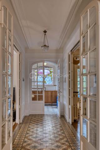 nouveau prix 775 000 euros FAI
Bienvenue dans cette villa, œuvre architecturale de Fernand César (1886-1969), associé et fils de l’architecte Félicien (1849-1930) livrée en 1912 à son commanditaire - l’industriel Adrien Humblot spécialiste de l’impression photographique - dans l’état que nous lui connaissons aujourd’hui. Elle sera habitée par François Streiff, doyen de la faculté de médecine et spécialiste de l’histoire artistique lorraine avant de l’être discrètement par les propriétaires actuels.

Toutes les façades -objet d’un soin architectural sans ostentation- s’articulent les unes aux autres avec bonheur par l’usage approprié du pan cassé. La façade sur rue sait exploiter le dénivelé sur rue et en profondeur grâce à l’horizontale du mur de clôture puis de soutènement en opus incertum de « mosaïque de roche ». Les éléments verticaux que sont la tour octogonale et la discrète entrée (que l’on dirait maçonnique) « écrivent » l’immeuble entre art nouveau et éclectisme.
1909, année de sa conception, correspond au chant du cygne du mouvement de l’École de Nancy. Les César sont reconnus pour une production architecturale polymorphe tant à Nancy, qu’à Vittel. Dès 1905 le fils seconde son père et s’en affranchit peu à peu mais continue de collaborer avec les artisans art nouveau de la seconde génération- ce qui ne manque pas de donner à cette villa toute sa singularité de dépouillement, de transition,  et de prélude à l’art déco dont nous fêtons le centenaire. 
Les interventions d’arts appliqués sont donc remarquablement mesurées : ferronneries, ébénisteries, céramiques, staff. Sauf celles de Jacques Gruber, qui foisonnent en un florilège de lumières, de compositions savantes au thème végétal et d’excellence des techniques mises en œuvre : grisailles, verres martelés, cabochons, gravures à l’acide…
Rappelons que le prolifique maître-verrier nancéien est l’auteur de vitraux pour la Chambre de Commerce et d’Industrie, la villa Majorelle et - avec les mêmes César - de l’immense verrière du siège nancéiens du Crédit Lyonnais.  

SUR UN PLAN PLUS TECHNIQUE…
Parlons chiffres d’abord : 
La surface utile totale est de 482 m2 décomposée ainsi :
Habitable : 315 m2
Annexes en sous-sol : 132 m2
Annexes aux étages et combles (compris surf. Planchers) : 35 m2
Non compris les surfaces de terrasses : 76 m2 (hors deck du jardin)
La contenance cadastrale est de 738 m2 développés en cœur d’ilot en jouxtant l’atelier sanctuarisé ayant vu la création du camouflage.
La consommation énergétique effectivement constatée sur base des factures est de 8000 à 8500 € l’an comprenant la production d’eau chaude sanitaire par cumulus électriques, le chauffage central produit par chaudière fuel et une consommation de bois d’environ 2 stères : bien loin des 20 000 € moyens issus du DPE. Malgré la médiocrité des performances théoriques, la maison s’avère confortable du fait de l’inertie de ses corps de chauffe surdimensionnés mais je ne peux cependant passer sous silence un comble démuni en période caniculaire mais qu’il serait aisé d’améliorer.
A la faveur de la récente rénovation, les réseaux électriques -intégralement encastrés- ont été renouvelés et complétés par un appareillage atemporel de boutons tournants.
La sécurité de la maison est assurée par détecteurs volumétriques et caméra pilotable.
Les revêtements de sol sont principalement de carreau en grès incrusté de Landrecies ou de parquet de chêne à pose en chevron. Les escaliers sont en comblanchien et doté de garde-corps en fer forgé. L’intervention contemporaine concerne le sol de béton peint des combles, le renforcement de toutes les canalisations et d’installations sanitaires supplémentaires.
La cuisine a fait l’objet d’un renouvellement récent par de nombreux agencements fonctionnels servis par de belles matières simples et nobles.
La maison dispose d’une telle quantité d’espaces servants en sous-sol et répartis aux étages que le mobilier peut être réduit à l’essentiel. 
Les dimensions généreuses du garage d’une hauteur supérieure à 270 cm lui permettent de stationner simultanément une berline voire un utilitaire et une moto. Le tout protégés par les vantaux d’origine coulissants, robustes et motorisés.

MAIS PLACE A LA VISITE !
Le rez-de-chaussée -réduit à sa fonction d’entrée- est mis en relation avec le bien-nommé « piano nobile » par un escalier vertigineusement théâtral qui nous amène directement au bureau.  Puis nous accédons à ce vaste hall central qui distribue les espaces de réception par un couple de portes à galandage vitrées qui favorisent ainsi avec la salle à-manger et le salon un espace de réception de quasiment 60 m2 voire de 75 m2 en ouvrant le jardin d’hiver. La partie fixe d’une salle-à-manger supposée d’Eugène Vallin côtoie une cheminée de gré émaillé de la maison Gentil-Bourdet et voit son radiateur équipé d’un chauffe-plat. Enfin, ce rez-de-jardin surélevé dispose de deux accès aux extérieurs, l’un par la cuisine et l’autre par le divin jardin d’hiver.
L’étage est doté d’une même hauteur sous plafond de 330 cm d’une même distribution centrée qui distribue 3 chambres, un immense dressing et la buanderie.
L’ascension se poursuit aux combles dotés de nombreuses surprises tel ce palier à l’énigmatique puits de lumière, cette chambre féeriquement monacale, une cabine de douche prodiguant musique chromothérapie et fonction de hammam et, encore plus inattendue, l’improbable roof-top de 50 m2 qui offre une vue panoramique sur la vieille ville et, par beau temps, jusqu’à la ligne bleue des Vosges.
Sur les deux niveaux nuit, la moitié des six chambres a une surface supérieure à 20 m2 et deux d’entre elles partagent une terrasse donnant sur le hêtre centenaire. La chambre parentale – 30 m2 compris sa salle d’eau privative- s’offre une triple orientation.
En résumé, avec une science consommée des harmonies, Fernand César offre une composition cruciforme de pièces toutes diversement personnalisées dans leurs proportions et qualifications (notamment par une dizaine de poêles et cheminées historiques) qui tire le meilleur parti de la course du soleil, du rapport équilibré au jardin arboré et des éléments qui y bruissent.
Parviendrons-nous - par nos mots et photographies- à restituer l’extrême pérennité des choix constructif de la villa, sa sobriété, gage d’une densité patrimoniale qui ne pèse jamais mais dont la consistance historique fait que chaque endroit du plus modeste au plus en vue témoigne avec simplicité de ce savoir-faire nancéien exceptionnel.

Hâte donc de vous y recevoir !

« Je voudrais de la lumière
Comme en Nouvelle Angleterre
Je veux changer d'atmosphère
Dans mon jardin d'hiver »