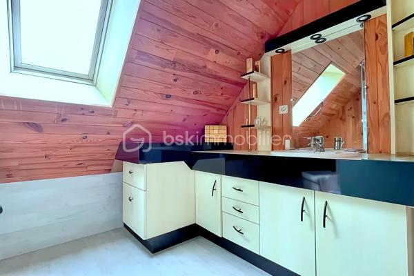 Située dans un cadre paisible et verdoyant, cette magnifique maison sur sous-sol complet offre des volumes généreux et des prestations de
qualité, idéales pour accueillir une grande famille.
Dès l'entrée, le ton est donné : l'espace s'ouvre sur une cuisine moderne, entièrement aménagée et équipée, pensée pour la convivialité.
Dans le prolongement, vous découvrirez un vaste salon-séjour baigné de lumière, où trône une cheminée à foyer fermé avec récupérateur de
chaleur, promesse de chaleureuses soirées d'hiver. Depuis cette pièce de vie, vous accédez directement à la terrasse, parfaite pour prolonger
vos journées en extérieur. Le rez-de-chaussée se complète d'un bureau fonctionnel, de deux belles chambres (dont une disposant de son
propre dressing), ainsi que d'une salle de bain tout confort avec douche à l'italienne et baignoire.
À l'étage, l'espace nuit se déploie pour offrir à chacun son intimité. Un coin détente et lecture accueille les moments calmes, desservant trois
chambres lumineuses et une salle d'eau indépendante.
Le sous-sol complet est un véritable atout pour les bricoleurs et le stockage. Accessible par une porte de garage motorisée, il abrite un grand
atelier, une buanderie, une arrière-cuisine ainsi qu'une cave.
Côté extérieur, vous profiterez d'un superbe terrain entièrement clos et arboré, véritable écrin de verdure à l'abri des regards. Techniquement
irréprochable, la maison bénéficie d'une bonne classe énergétique (D) grâce à des menuiseries en double vitrage récentes, et la toiture est
garantie sans aucune présence d'amiante.
Une opportunité rare sur le secteur, où il ne reste plus qu'à poser vos valises. À visiter sans tarder !