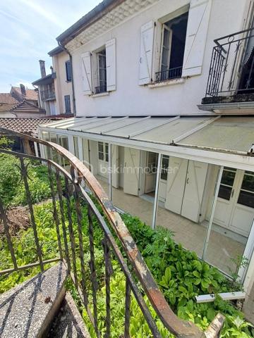 Au coeur du centre bourg de La Bastide-de-Sérou, découvrez une demeure de caractère imprégnée d’un récit hors du commun. Cette maison
n’est pas qu’une simple bâtisse : elle fut le siège d'une étude notariale emblématique. Son histoire raconte l'histoire de la première femme
notaire de France, qui, suite au décès brutal de son père, reprit le flambeau et l'étude familiale avec détermination. Aujourd'hui, cette demeure
chargée d'histoire n'attend que votre vision pour retrouver son lustre d'antan.

La Demeure
Érigée en 1850, cette maison de village mitoyenne développe environ 216 m² habitables répartis sur trois niveaux, offrant de beaux volumes
et le charme authentique des constructions du XIXe siècle.
Rez-de-chaussée : L'entrée, autrefois lieu d'accueil de l'étude, dessert un salon, une cuisine, une salle de bain et des toilettes. Ce niveau
comprend également une chaufferie et offre un accès direct à une véranda de 17 m², véritable trait d'union vers votre futur jardin.
Premier étage : Un palier vestibule distribue trois chambres, dont une suite avec salle de bain, ainsi qu'une pièce dédiée au dressing. Vous
profiterez d'un accès privilégié à un toit-terrasse d'environ 18 m², idéal pour vos moments de quiétude.
Deuxième étage : Le charme des combles et des volumes atypiques. Cet étage comprend un palier, une chambre avec sa cheminée
d'époque (17 m²), une pièce annexe de 6 m², ainsi que deux grands greniers totalisant 54 m² offrant un potentiel d'aménagement
spectaculaire.

Extérieur
Le bien dispose d'un terrain privatif d'environ 200 m², une rareté au coeur d'un centre bourg. Un espace extérieur intime, propice à la création
d'un jardin paysager à votre image.

Située dans une rue calme, cette propriété bénéficie de la proximité immédiate de toutes les commodités, services et commerces de La
Bastide-de-Sérou. Un emplacement stratégique alliant vie de village et accès facilité.

Le Projet
Cette maison de prestige nécessite une rénovation globale (toiture/charpente en bon état). C'est l'opportunité rare de conjuguer une histoire
familiale riche avec un projet de vie sur-mesure, en redonnant vie à des espaces dont les murs ont été les témoins d'un destin exceptionnel.

Amoureux des vieilles pierres, investisseurs ou passionnés d'histoire, venez écrire le prochain chapitre de cette demeure unique.