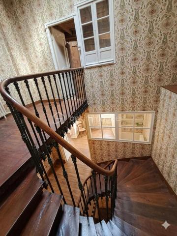Au coeur du centre bourg de La Bastide-de-Sérou, découvrez une demeure de caractère imprégnée d’un récit hors du commun. Cette maison
n’est pas qu’une simple bâtisse : elle fut le siège d'une étude notariale emblématique. Son histoire raconte l'histoire de la première femme
notaire de France, qui, suite au décès brutal de son père, reprit le flambeau et l'étude familiale avec détermination. Aujourd'hui, cette demeure
chargée d'histoire n'attend que votre vision pour retrouver son lustre d'antan.

La Demeure
Érigée en 1850, cette maison de village mitoyenne développe environ 216 m² habitables répartis sur trois niveaux, offrant de beaux volumes
et le charme authentique des constructions du XIXe siècle.
Rez-de-chaussée : L'entrée, autrefois lieu d'accueil de l'étude, dessert un salon, une cuisine, une salle de bain et des toilettes. Ce niveau
comprend également une chaufferie et offre un accès direct à une véranda de 17 m², véritable trait d'union vers votre futur jardin.
Premier étage : Un palier vestibule distribue trois chambres, dont une suite avec salle de bain, ainsi qu'une pièce dédiée au dressing. Vous
profiterez d'un accès privilégié à un toit-terrasse d'environ 18 m², idéal pour vos moments de quiétude.
Deuxième étage : Le charme des combles et des volumes atypiques. Cet étage comprend un palier, une chambre avec sa cheminée
d'époque (17 m²), une pièce annexe de 6 m², ainsi que deux grands greniers totalisant 54 m² offrant un potentiel d'aménagement
spectaculaire.

Extérieur
Le bien dispose d'un terrain privatif d'environ 200 m², une rareté au coeur d'un centre bourg. Un espace extérieur intime, propice à la création
d'un jardin paysager à votre image.

Située dans une rue calme, cette propriété bénéficie de la proximité immédiate de toutes les commodités, services et commerces de La
Bastide-de-Sérou. Un emplacement stratégique alliant vie de village et accès facilité.

Le Projet
Cette maison de prestige nécessite une rénovation globale (toiture/charpente en bon état). C'est l'opportunité rare de conjuguer une histoire
familiale riche avec un projet de vie sur-mesure, en redonnant vie à des espaces dont les murs ont été les témoins d'un destin exceptionnel.

Amoureux des vieilles pierres, investisseurs ou passionnés d'histoire, venez écrire le prochain chapitre de cette demeure unique.