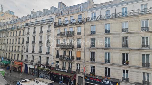 À deux pas du canal de l’Ourcq et de Stalingrad, découvrez ce T2 de 30,4 m² Carrez, au 5ᵉ étage sans ascenseur, dans un immeuble ancien avec cachet avec balcon filant.
L’appartement est très lumineux, avec 3 grandes fenêtres pleine hauteur et une vue dégagée (Sacré-Cœur visible en hiver + métro aérien Stalingrad (pas bruyant).

Disposition
	•	Pièce principale (chambre/séjour), très lumineuse avec 2 portes-fenêtres ouvrant sur le balcon
	•	Grande cuisine avec coin repas (fenêtre sur balcon)
	•	Salle d’eau - équipée d’un sanibroyeur
	•	WC individuel sur le patio, privatif, accessible par clé (avec éclairage rattaché au logement)
	•	Cave au sous-sol

L’appartement nécessite une rénovation intérieure. Appartement laissé volontairement brut, offrant une belle base à réinventer (distribution optimisable selon vos envies). 
 Ballon d’eau chaude présent, mais pas encore posé (en cours). Le DPE n’a pas été réalisé car aucun radiateur électrique n’est actuellement installé, bien que sur la photo, un petit poêle a été installé après, à la fois décoratif et efficace à temps très froid.

➡️ Ravalement voté par la copropriété, avec une réalisation prévue en 2026 (sous réserve du calendrier de la copropriété). Le propriétaire indique que la totalité du montant correspondant à sa quote-part a été réglée.

📌 Charges faibles
📌 Fibre optique dans l’immeuble
📌 Cabinet dentaire présent au 1er étage
📌 Commerces, transports et arrêt de bus Château-Landon au pied de l’immeuble