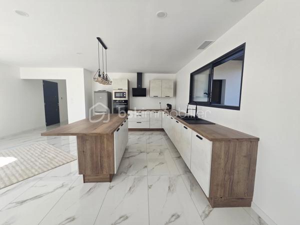 Découvrez cette belle maison contemporaine de plain-pied, offrant des prestations modernes et des espaces pensés pour un quotidien confortable.

✨ Dès l’entrée, vous serez séduits par la luminosité et les volumes de la pièce de vie. Celle-ci accueille une superbe cuisine ouverte entièrement aménagée et équipée, aux lignes contemporaines, avec un généreux îlot central créant un espace convivial idéal pour recevoir famille et amis.

🌿 De larges ouvertures permettent de profiter pleinement de la lumière naturelle et donnent accès à une agréable terrasse couverte, véritable prolongement de la pièce de vie pour profiter des beaux jours.

🛏️ La partie nuit propose des espaces sobres et lumineux, facilement personnalisables selon vos envies. La maison dispose également d’une salle de bains moderne, équipée notamment d’une baignoire et d'un meuble vasque, dans une ambiance élégante et actuelle.
🚗 Un garage attenant complète l'ensemble et apporte un espace supplémentaire appréciable pour le stationnement et le rangement.

À l’extérieur, l’architecture contemporaine, les menuiseries foncées et la toiture en tuiles confèrent à cette maison une allure à la fois moderne et chaleureuse.

❤️ Les atouts :
• Maison de plain-pied
• Construction contemporaine
• Belle luminosité
• Grande pièce de vie
• Cuisine aménagée et équipée avec îlot central
• Terrasse couverte
• Salle de bains moderne
• Garage attenant
• Prestations actuelles et décoration neutre, prête à accueillir ses nouveaux propriétaires