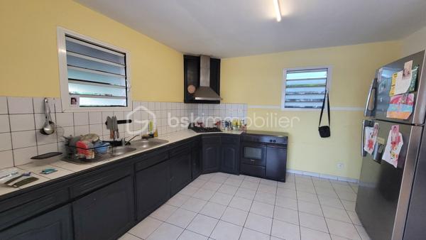 Vente Maison familiale de plain-pied de 97 m² avec terrasse, idéalement située dans le quartier résidentiel des Jacques à Saint-Joseph, proche des écoles et des commodités. Cette maison de plain-pied de 97 m² habitables saura séduire les acquéreurs en quête d'un bien fonctionnel et bien agencé, que ce soit pour y établir leur résidence principale ou pour réaliser un investissement locatif. 

Implantée dans un environnement calme et agréable, cette propriété bénéficie d'une bonne exposition et d'une construction solide en dur, avec toiture tôle et chauffe-eau solaire.

Dès l'entrée, d'une superficie de 3,60 m², vous accédez à la cuisine et l'espace de distribution bien pensé qui dessert l'ensemble des pièces de vie et des chambres. 

Le salon, vaste et lumineux, offre une superficie de 24,80 m². Il bénéficie d'une belle hauteur sous plafond et d'un accès direct sur la terrasse extérieure par l'intermédiaire d'une baie vitrée coulissante. L'espace de vie est prolongé par un hall terrasse de 9,40 m², créant une continuité agréable entre l'intérieur et l'extérieur, idéal pour profiter du cadre réunionnais tout au long de l'année. 

La cuisine, d'une superficie de 14,40 m² dispose d'une implantation en L avec de nombreux meubles de rangement, d'une plaque de cuisson, d'une hotte aspirante, et est dotée de fenêtres à jalousies garantissant une ventilation naturelle optimale. Fonctionnelle et agréable, elle conviendra parfaitement aux familles. 

Le couloir de 5 m² dessert les trois chambres, la salle de bain et le WC indépendant. Les trois chambres sont dotées de fenêtres assurant un bon renouvellement de l'air, présentent des superficies généreuses et confortables :

Chambre 1 : 12,20 m²
Chambre 2 : 10,40 m²
Chambre 3 : 11 m²

La salle de bain de 4,40 m² est équipée d'une baignoire d'angle, d'une vasque encastrée et d'un miroir. Elle dispose d'une fenêtre permettant une aération naturelle. Le WC, séparé de la salle de bain, offre une superficie de 1,80 m².

L'extérieur de la propriété constitue un véritable atout supplémentaire. La maison dispose d'une terrasse couverte de 16 m², parfaitement adaptée aux repas en plein air et aux moments de convivialité en famille ou entre amis. 

Une terrasse couvert supplémentaire aménagée avec une structure en bois et une toiture en tôle, accessible depuis l'extérieur, offre un espace de rangement. Le terrain entourant la maison dispose d'espaces verts, apportant une note de verdure et de sérénité à l'ensemble. 

La maison est implantée sur un terrain d'une superficie de 465 m², offrant un espace extérieur agréable autour de la maison. Concernant l'assainissement, la maison est équipée d'une fosse septique. 

Informations locatives
Ce bien est proposé à la vente et est actuellement occupé. Il est loué dans le cadre d'un bail d'habitation nu, avec des locataires en place jusqu'au 31 janvier 2027.

Le loyer mensuel en cours s'élève à 768 euros hors charges. Cette configuration permet à l'acquéreur de percevoir des revenus locatifs dès la signature de l'acte authentique, tout en se constituant un patrimoine immobilier dans un secteur résidentiel de Saint-Joseph.

Pour organiser une visite ou obtenir des informations complémentaires, contactez-moi.