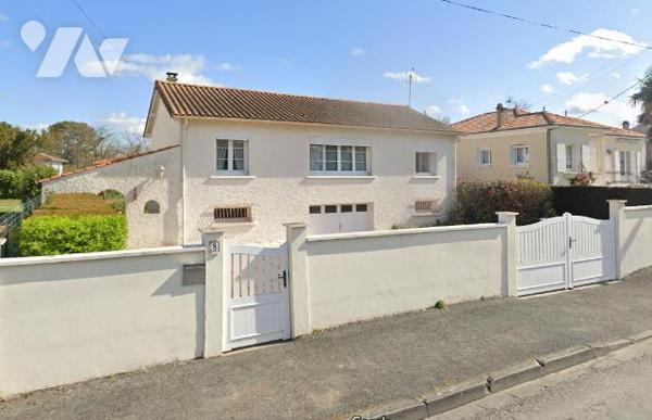 Maison de ville a étage avec un grand jardin arboré.
