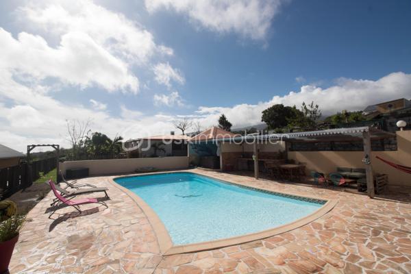 Quartier Jean Petit - 450m d'altitude - Terrain 1159 m²

Découvrez cette magnifique propriété familiale alliant confort, vue exceptionnelle et potentiel locatif !
Nichée à 450 mètres d'altitude dans le paisible et recherché quartier de Jean Petit à Saint-Joseph, cette villa F5 construite en 2005 vous offre un cadre de vie privilégié avec une vue mer et montagne à couper le souffle. Édifiée sur une parcelle entièrement clôturée de 1159 m², dans un chemin au calme, à l'écart de la circulation.

Équipements haut de gamme : piscine chauffée, jacuzzi et panneaux photovoltaïques neufs pour un confort optimal et des économies d'énergie !
La Maison Principale - 150 m² (Loi Carrez)

Rez-de-Chaussée
Un espace de vie généreux de 54 m² baigné de lumière naturelle :

Cuisine ouverte équipée de 23 m²
Salon spacieux avec accès à la piscine
Coin bureau/bibliothèque/salle de jeux de 13 m² attenant au salon

Un espace nuit parfaitement conçu avec 3 chambres :

Chambre 1 : 21 m² avec salle de douche privative
Chambre 2 : 15 m² avec salle de douche et WC privatifs
Chambre 3 : 13 m² avec salle de douche privative
Un WC indépendant

Étage
Une suite parentale d'exception de 25 m² :

Chambre spacieuse et lumineuse
Salle de douche à l'italienne moderne
WC privatif
Balcon avec vue panoramique mer, montagne et piscine
Coin bureau de 3,6 m² idéal pour le télétravail

Sous-Sol
Garage de 60 m² accessible par escalier intérieur :

Espace de stationnement sécurisé
Multiples possibilités de rangement
Potentiel d'aménagement (atelier, cave, salle de sport...)

Le Gîte Indépendant T2 - 60 m²
Situé en fond de jardin, ce gîte totalement autonome offre un excellent potentiel locatif :

Entrée spacieuse et accueillante
Cuisine ouverte équipée sur espace de vie
Salon/espace détente de 7 m²
Chambre de 11 m² confortable
Salle de douche avec WC de 5 m²
Terrasse privative pour profiter du jardin

Parfait pour accueillir famille, amis ou générer un revenu locatif régulier dans une zone touristique prisée.

Les Atouts de cette Propriété
✓ Parcelle de 1159 m² entièrement clôturée : Intimité et sécurité garanties
✓ Emplacement au calme : Chemin sans circulation, idéal pour les enfants
✓ Vue mer et montagne : Panorama exceptionnel depuis la suite parentale
✓ Grande piscine chauffée : Baignade agréable toute l'année
✓ Jacuzzi en coque : Espace bien-être et détente à domicile
✓ Panneaux photovoltaïques neufs (2024) : Économies d'énergie et revenus de revente
✓ Double habitation : Maison F5 (150 m²) + Gîte T2 (60 m²)
✓ 4 chambres dont 1 suite parentale avec balcon panoramique
✓ 4 salles de douche : Confort optimal pour toute la famille
✓ Garage 60 m² en sous-sol avec accès intérieur
✓ Construction 2005 : Bien entretenu et aux normes actuelles
✓ Potentiel locatif : Revenus complémentaires avec le gîte indépendant

Le Quartier Jean Petit - Un Cadre de Vie Idéal
Quartier familial et prisé où il fait bon vivre, Jean Petit offre toutes les commodités à proximité immédiate :

Services de santé :
Médecin
Pharmacie
Kinésithérapeute

Éducation :
École maternelle
École primaire

Loisirs et commerces de proximités :
Piscine municipale
Terrains de sport
Épicerie de proximité

Un quartier vivant et convivial, parfait pour une vie de famille épanouie !

Caractéristiques Techniques :
Surface totale habitable : 210 m²
Maison principale : 150 m² (Loi Carrez)
Gîte indépendant : 60 m²

Garage en sous-sol : 60 m²
Terrain : 1159 m² entièrement clos
Année de construction : 2005
Altitude : 450 mètres

Équipements premium :
Piscine chauffée
Jacuzzi en coque
Panneaux photovoltaïques installés en 2024

Une propriété rare alliant qualité de vie exceptionnelle, vue imprenable, environnement familial et opportunité d'investissement. Idéale pour une famille recherchant confort, espace et tranquillité avec un potentiel de revenus locatifs.

Pour plus d'informations et organiser une visite de ce bien d'exception, contactez moi, Eloïse Casotto Conseillère BSK Immobilier au 06 92 08 16 38 ou par mail à ecasotto@bskimmobilier.com.