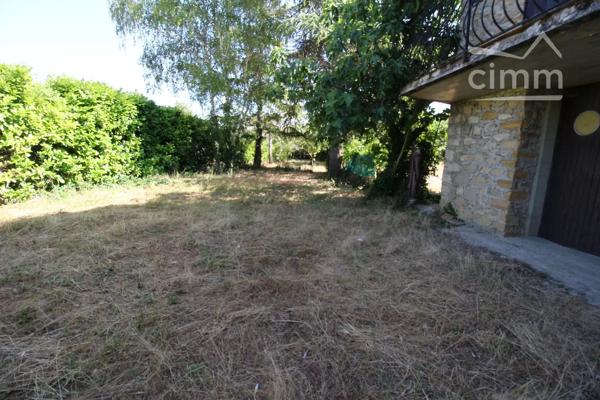 A vendre une grande maison en pierre avec un jardin clôturé, un grand garage de 132m² et une grange de 30m².