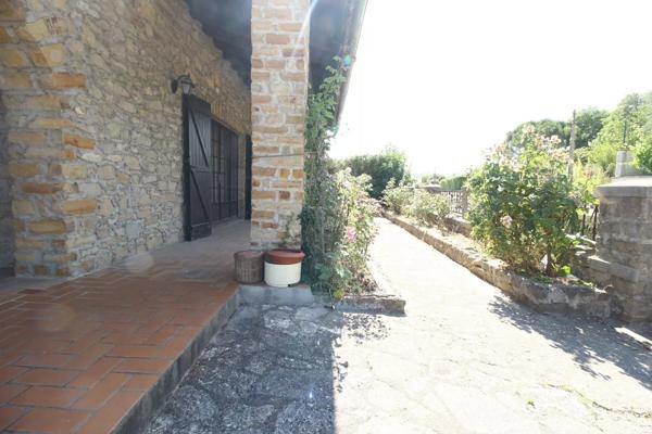A vendre une grande maison en pierre avec un jardin clôturé, un grand garage de 132m² et une grange de 30m².