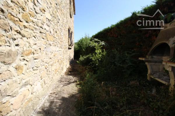 A vendre une grande maison en pierre avec un jardin clôturé, un grand garage de 132m² et une grange de 30m².