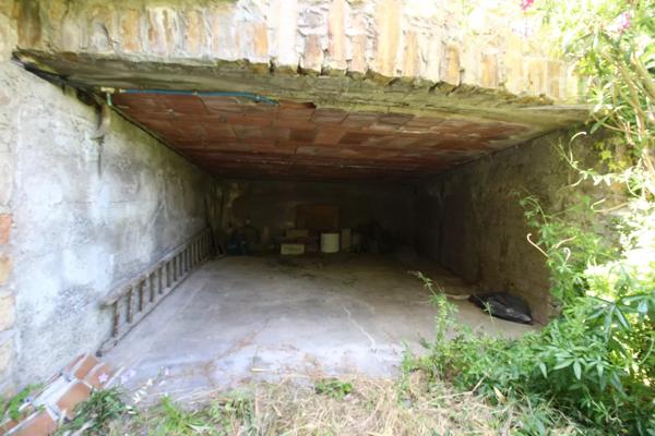 A vendre une grande maison en pierre avec un jardin clôturé, un grand garage de 132m² et une grange de 30m².