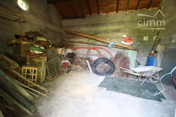 A vendre une grande maison en pierre avec un jardin clôturé, un grand garage de 132m² et une grange de 30m².