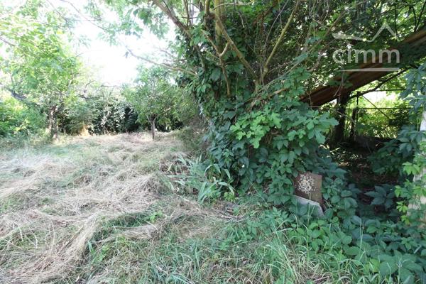 A vendre une grande maison en pierre avec un jardin clôturé, un grand garage de 132m² et une grange de 30m².