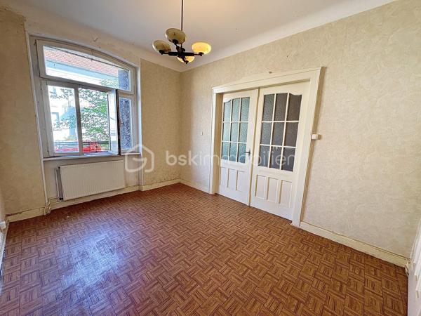 Située à Sarreguemines, cette maison mitoyenne d’un côté, d’environ 135 m², offre un beau potentiel pour les amateurs de rénovation et les projets immobiliers.

Répartie sur plusieurs niveaux, elle dispose actuellement de nombreux espaces pouvant être repensés selon les besoins : au rez-de-chaussée, vous trouverez notamment un séjour, un salon, une cuisine, une chambre ainsi qu’une salle d’eau.

Le premier étage propose également plusieurs pièces de vie, une cuisine, une chambre et une salle de bains. Les combles offrent quant à eux deux espaces supplémentaires pouvant être aménagés en chambres ou selon les envies.

La maison bénéficie également d’une petite loggia fermée accessible depuis l’étage, apportant un espace supplémentaire et une ouverture agréable sur l’extérieur.

La configuration actuelle, avec ses différents espaces et ses deux cuisines, peut permettre d’envisager plusieurs projets : créer une grande habitation familiale, repenser entièrement les volumes ou réfléchir à un projet locatif, sous réserve des travaux et autorisations nécessaires.

À l’extérieur, le bien dispose d’un garage pouvant accueillir deux véhicules, d’une cave ainsi que d’un grand jardin à l’arrière.

L’ensemble nécessite une rénovation complète. Cette maison s’adresse donc particulièrement aux personnes à la recherche d’un véritable projet de rénovation, avec la possibilité de transformer et de moderniser les espaces selon leurs besoins et leurs envies.

Une belle opportunité pour révéler le potentiel de cette ancienne maison et lui donner une nouvelle vie.