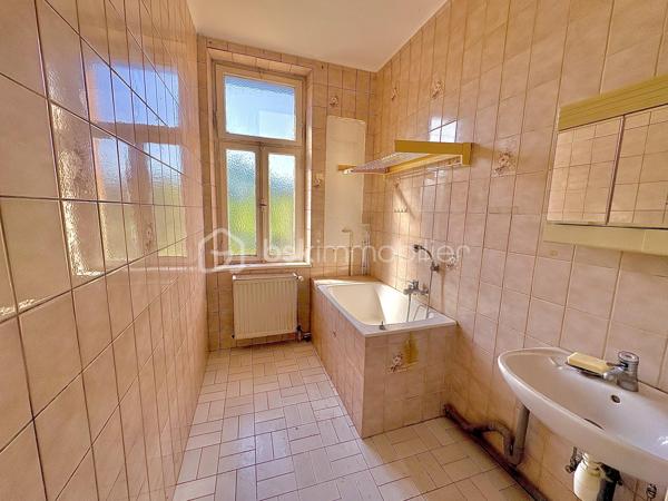 Située à Sarreguemines, cette maison mitoyenne d’un côté, d’environ 135 m², offre un beau potentiel pour les amateurs de rénovation et les projets immobiliers.

Répartie sur plusieurs niveaux, elle dispose actuellement de nombreux espaces pouvant être repensés selon les besoins : au rez-de-chaussée, vous trouverez notamment un séjour, un salon, une cuisine, une chambre ainsi qu’une salle d’eau.

Le premier étage propose également plusieurs pièces de vie, une cuisine, une chambre et une salle de bains. Les combles offrent quant à eux deux espaces supplémentaires pouvant être aménagés en chambres ou selon les envies.

La maison bénéficie également d’une petite loggia fermée accessible depuis l’étage, apportant un espace supplémentaire et une ouverture agréable sur l’extérieur.

La configuration actuelle, avec ses différents espaces et ses deux cuisines, peut permettre d’envisager plusieurs projets : créer une grande habitation familiale, repenser entièrement les volumes ou réfléchir à un projet locatif, sous réserve des travaux et autorisations nécessaires.

À l’extérieur, le bien dispose d’un garage pouvant accueillir deux véhicules, d’une cave ainsi que d’un grand jardin à l’arrière.

L’ensemble nécessite une rénovation complète. Cette maison s’adresse donc particulièrement aux personnes à la recherche d’un véritable projet de rénovation, avec la possibilité de transformer et de moderniser les espaces selon leurs besoins et leurs envies.

Une belle opportunité pour révéler le potentiel de cette ancienne maison et lui donner une nouvelle vie.