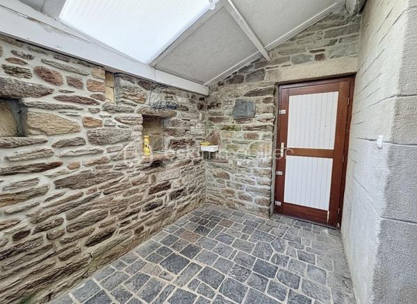 À seulement 10 minutes de LANDIVISIAU et idéalement située au cœur du bourg de PLOUVORN, à proximité immédiate des commodités, venez découvrir cette authentique maison en pierre datant de 1910, pleine de charme et de potentiel.

Édifiée sur une parcelle de plus de 500 m², cette bâtisse de caractère séduira les amateurs d'ancien grâce à ses murs en pierre apparente, présents aussi bien à l'extérieur qu'à l'intérieur.

Au rez-de-chaussée, vous trouverez une pièce de vie comprenant salon et salle à manger, une cuisine aménagée et équipée offrant de nombreux rangements, un espace avec évier et rangements complémentaires, un WC ainsi qu'un sas donnant accès au jardin.

Le premier étage dessert une pièce pouvant faire office de bureau, dressing ou chambre d'appoint, une salle d'eau, un WC indépendant ainsi que deux chambres.

Le second étage offre plusieurs espaces supplémentaires à aménager selon vos envies : chambres, suite parentale, salle de jeux ou bureau. Un véritable potentiel d'agrandissement s'offre à vous.

À l'extérieur, vous profiterez d'un jardin agréable avec barbecue en pierre. Un grand garage avec porte motorisée permet de stationner un véhicule et dispose également d'un espace aménageable à l'étage. Plusieurs dépendances et locaux de stockage complètent l'ensemble, offrant de nombreuses possibilités d'aménagement.

Cette maison mitoyenne d'un côté nécessite des travaux de rénovation afin de valoriser pleinement le bien, notamment sur certains éléments d’entretien et d’amélioration énergétique. La toiture a cependant fait l’objet d’une rénovation partielle récente en 2025, apportant un premier élément de sécurisation du bâti mais constitue une opportunité rare pour les amoureux des belles pierres souhaitant créer un lieu de vie à leur image.

Ce bien au fort potentiel s’adresse à des acquéreurs souhaitant entreprendre un projet de rénovation et de valorisation d’une maison de caractère en pierre.

Le mobilier actuellement présent pourra être conservé par les acquéreurs ou retiré avant la vente selon les besoins.
À découvrir sans tarder.