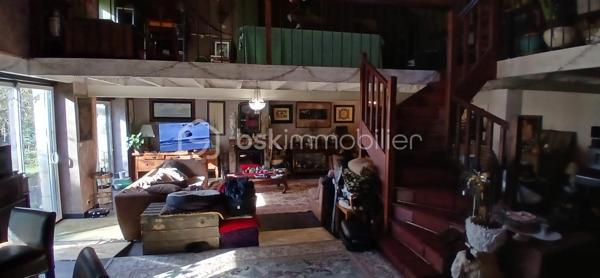 À seulement 1 km maximum de la ville et de toutes les commodités, au bout d’un chemin paisible où le silence n’est troublé que par la nature, découvrez cette magnifique maison en pierres de taille et moellons datant des années 1900, non mitoyenne, nichée au cœur d’un écrin de verdure de 5 191 m². Une propriété rare de 379 m² habitables, idéale pour les amoureux de calme, d’espace et d’authenticité.

Dès l’entrée, les volumes impressionnent : un séjour de 64 m² sublimé par une mezzanine de 40 m² qui surplombe la pièce et renforce le cachet et le caractère des lieux, un petit salon plus intime pour recevoir, une grande salle à manger conviviale et une cuisine séparée, moderne, aménagée et équipée. La maison offre au rez-de-chaussée une belle chambre de 20 m² avec sa suite parentale comprenant salle de bain, douche et toilettes séparées, ainsi qu’un WC indépendant. Deux cheminées agrémentent la maison, dont une avec insert, apportant chaleur et atmosphère d’antan. Au rez-de-chaussée, les ouvertures sont en double vitrage bois et les baies vitrées en aluminium, alliant confort et respect du style de la bâtisse.

À l’étage, trois chambres de 17 m², 14 m² et 13 m² se partagent un palier de 8 m². Les fenêtres y sont en simple vitrage, conservant l’esprit authentique de l’étage.

Un studio indépendant de 60 m², entièrement refait à neuf, complète ce bien et offre de très belles possibilités. Il dispose d’une chambre de 16 m², d’une agréable pièce de vie de 25 m² avec cuisine équipée, d’une salle de bain neuve, d’une salle d’eau avec cabine de douche, d’un WC séparé ainsi que d’un coin nuit avec lits superposés. À l’entrée du studio, une terrasse avec auvent accueille table et chaises pour profiter des beaux jours en toute tranquillité. Idéal pour recevoir famille et amis, développer une activité professionnelle ou envisager un projet locatif.

À l’extérieur, le terrain arboré de 5 191 m² invite à la détente avec une piscine 9 x 4,5 m, une cuisine d’été, un grand garage de 130 m² et une cave. La toiture est en bon état. L’assainissement est individuel et non conforme.

Le DPE est classé C en performance énergétique et A en émissions de gaz à effet de serre, un excellent équilibre pour une demeure de caractère. La maison est équipée d’une chaudière à pellets nouvelle génération assurant un confort performant et économique.

Les matériaux utilisés sont de bonne qualité, alliant robustesse et longévité, dans le respect du bâti ancien. Cette propriété séduira particulièrement les amoureux de l’authenticité, de la pierre et des demeures de caractère, à la recherche d’un lieu chargé d’histoire où le charme de l’ancien s’exprime pleinement, tout en restant proche de la ville.