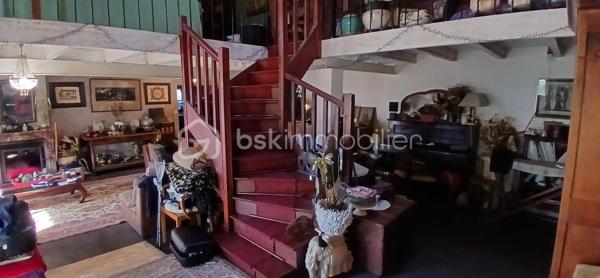 À seulement 1 km maximum de la ville et de toutes les commodités, au bout d’un chemin paisible où le silence n’est troublé que par la nature, découvrez cette magnifique maison en pierres de taille et moellons datant des années 1900, non mitoyenne, nichée au cœur d’un écrin de verdure de 5 191 m². Une propriété rare de 379 m² habitables, idéale pour les amoureux de calme, d’espace et d’authenticité.

Dès l’entrée, les volumes impressionnent : un séjour de 64 m² sublimé par une mezzanine de 40 m² qui surplombe la pièce et renforce le cachet et le caractère des lieux, un petit salon plus intime pour recevoir, une grande salle à manger conviviale et une cuisine séparée, moderne, aménagée et équipée. La maison offre au rez-de-chaussée une belle chambre de 20 m² avec sa suite parentale comprenant salle de bain, douche et toilettes séparées, ainsi qu’un WC indépendant. Deux cheminées agrémentent la maison, dont une avec insert, apportant chaleur et atmosphère d’antan. Au rez-de-chaussée, les ouvertures sont en double vitrage bois et les baies vitrées en aluminium, alliant confort et respect du style de la bâtisse.

À l’étage, trois chambres de 17 m², 14 m² et 13 m² se partagent un palier de 8 m². Les fenêtres y sont en simple vitrage, conservant l’esprit authentique de l’étage.

Un studio indépendant de 60 m², entièrement refait à neuf, complète ce bien et offre de très belles possibilités. Il dispose d’une chambre de 16 m², d’une agréable pièce de vie de 25 m² avec cuisine équipée, d’une salle de bain neuve, d’une salle d’eau avec cabine de douche, d’un WC séparé ainsi que d’un coin nuit avec lits superposés. À l’entrée du studio, une terrasse avec auvent accueille table et chaises pour profiter des beaux jours en toute tranquillité. Idéal pour recevoir famille et amis, développer une activité professionnelle ou envisager un projet locatif.

À l’extérieur, le terrain arboré de 5 191 m² invite à la détente avec une piscine 9 x 4,5 m, une cuisine d’été, un grand garage de 130 m² et une cave. La toiture est en bon état. L’assainissement est individuel et non conforme.

Le DPE est classé C en performance énergétique et A en émissions de gaz à effet de serre, un excellent équilibre pour une demeure de caractère. La maison est équipée d’une chaudière à pellets nouvelle génération assurant un confort performant et économique.

Les matériaux utilisés sont de bonne qualité, alliant robustesse et longévité, dans le respect du bâti ancien. Cette propriété séduira particulièrement les amoureux de l’authenticité, de la pierre et des demeures de caractère, à la recherche d’un lieu chargé d’histoire où le charme de l’ancien s’exprime pleinement, tout en restant proche de la ville.