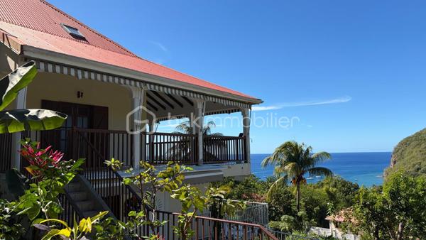 Découvrez cette magnifique propriété de 2 031 m² idéalement située sur les hauteurs de Deshaies, offrant une vue panoramique exceptionnelle sur la baie et un cadre de vie privilégié.

Cette propriété se distingue par ses volumes généreux, ses nombreuses ouvertures qui inondent les espaces de lumière naturelle tout au long de la journée et sa ventilation traversante, particulièrement appréciable sous le climat tropical. Les chambres climatisées assurent un confort optimal en toutes saisons.

La villa principale, aux prestations de qualité, s'organise autour d'une vaste pièce de vie baignée de lumière, sublimée par une remarquable hauteur sous plafond et une mezzanine ouverte qui accentue la sensation d'espace. La cuisine, conviviale et fonctionnelle, s'intègre harmonieusement à cet espace de vie. L'espace nuit comprend quatre chambres, dont une belle suite parentale. À l'extérieur, une vaste terrasse panoramique prolonge les pièces de vie et offre une vue imprenable sur la baie de Deshaies, idéale pour profiter des couchers de soleil.

La propriété comprend également deux appartements T2 totalement indépendants, parfaits pour accueillir famille et amis ou développer une activité de location saisonnière. Chaque T2 est composé d'une cuisine ouverte sur le séjour, d'une chambre, d'une salle d'eau et d'une terrasse privative permettant de profiter pleinement de l'environnement tropical en toute intimité.

Avec un total de 9 pièces, cette propriété représente une opportunité rare, alliant confort, potentiel locatif et qualité de vie.

Son emplacement est un véritable atout : à seulement quelques minutes des plages emblématiques de Grande Anse, des commerces, des restaurants et du charmant bourg de Deshaies, elle offre un équilibre parfait entre tranquillité, proximité des commodités et attractivité touristique.

Que vous recherchiez une résidence principale, une maison de vacances ou un investissement à fort potentiel, cette propriété saura vous séduire par son emplacement exceptionnel, ses prestations et son panorama unique sur l'une des plus belles baies de Guadeloupe.