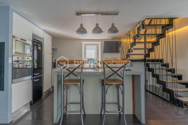 À Ferrières, dans un environnement calme et préservé, au cœur d’un cadre naturel entouré de montagnes, découvrez ce superbe duplex de 124 m², offrant un excellent compromis entre maison et appartement.

Situé dans un ancien corps de ferme, ce bien a été entièrement rénové avec goût. Il séduit par ses beaux volumes, sa circulation fluide entre les espaces et son atmosphère chaleureuse.

Au rez-de-chaussée, vous profitez d’une grande pièce de vie lumineuse de plus de 50 m², comprenant une cuisine ouverte, un espace repas et un salon. Moderne et fonctionnelle, la cuisine s’articule autour d’un îlot central convivial. Depuis la pièce de vie, vous accédez à une agréable terrasse en bois, idéale pour profiter du calme environnant. Un petit potager vient compléter ce bel extérieur.

Ce niveau dispose également d’une buanderie ainsi que d’un WC indépendant.

Un élégant escalier en métal apporte du caractère à l’ensemble et mène à l’étage. Une verrière ouvre les perspectives et renforce la luminosité de la mezzanine.

L’espace nuit se compose actuellement de deux chambres et d’une grande mezzanine, pouvant facilement être transformée en troisième chambre.

La chambre parentale, d’environ 20 m², bénéficie d’un dressing ainsi que d’une salle d’eau complète avec baignoire, douche et WC. La seconde chambre, d’environ 13 m², dispose également de sa propre douche.

Toiture et façade récentes, aucun travaux à prévoir.

Le bien fait partie d’une copropriété bénévole, sans frais de copropriété. Le chauffage est collectif avec comptage individuel, complété par un poêle à granulés apportant confort et convivialité.

Ce duplex dispose également de deux places de parking ainsi que d’une cave.

La commune de Ferrières offre un cadre naturel recherché, à proximité immédiate de la Mandallaz et à moins de 10 minutes de l’accès autoroute permettant de rejoindre Genève.

Un bien atypique et chaleureux, idéal pour ceux qui recherchent les volumes et le confort d’une maison, tout en conservant les avantages d’un appartement.