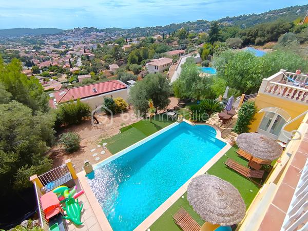 OLLIOULES – LA COURTINE

Villa avec vue panoramique, piscine à débordement et appartement indépendant

Une vue panoramique dont on ne se lasse jamais, une piscine à débordement semblant se fondre dans le paysage et un environnement préservé à quelques minutes seulement du centre d'Ollioules.

Dans l'un des secteurs résidentiels les plus recherchés de la commune, cette propriété offre un cadre de vie privilégié où intimité, lumière et panorama exceptionnel se conjuguent au quotidien.

Nichée au bout d'une impasse, à l'abri des regards, cette élégante villa construite en 2003 développe environ 225 m² habitables sur un terrain paysager de 1 662 m².

Dès les premiers instants, le charme opère.

Les volumes généreux, la luminosité omniprésente et l'ouverture permanente sur l'extérieur créent une atmosphère à la fois chaleureuse et apaisante.

Le niveau principal accueille plus de 100 m² de plain-pied baignés de lumière grâce à son exposition Sud-Sud-Ouest.

Il comprend :

• Une entrée avec dressing
• Un vaste espace de vie de près de 64 m² avec cheminée
• Une cuisine familiale entièrement équipée
• Une suite parentale avec salle d'eau privative et accès direct à la terrasse

Chaque espace profite pleinement de la vue spectaculaire qui accompagne le quotidien et prolonge naturellement les pièces de vie vers l'extérieur.

À l'étage, l'espace nuit accueille trois chambres bénéficiant chacune d'un accès direct au balcon panoramique ainsi qu'un bureau pouvant faire office de chambre supplémentaire, d'espace télétravail ou de salle de loisirs. Les autres espaces nuit se répartissent entre le niveau principal et l'appartement indépendant.

Pensée pour accueillir famille et amis dans les meilleures conditions, la propriété dispose également d'un appartement indépendant d'environ 54 m² avec terrasse privative.

Véritable atout de la propriété, cet espace complémentaire permet de recevoir en toute intimité, d'exercer une activité professionnelle indépendante ou d'envisager un revenu locatif.

À l'extérieur, le spectacle continue.

La piscine à débordement de 9 x 4 mètres semble se fondre dans le paysage et offre un point de vue privilégié sur les collines du littoral varois.

Les terrasses, espaces détente et coins repas invitent à profiter pleinement du climat méditerranéen et des couchers de soleil qui rythment les saisons.

Deux vastes restanques supplémentaires offrent encore de nombreuses possibilités d'aménagement selon vos envies : jardin méditerranéen, terrain de pétanque, espace de loisirs ou projet paysager personnalisé.

Les prestations :

• Environ 225 m² habitables
• Terrain de 1 662 m²
• Construction de 2003
• 5 chambres + 1 bureau
• 3 salles d'eau dont une à personnaliser
• Appartement indépendant de 54 m²
• Piscine à débordement 9 x 4 m
• Pompe à chaleur récente (2024)
• Climatisation réversible
• Double vitrage
• Garage de 20 m²
• Nombreuses places de stationnement
• Portail automatique

À seulement quelques minutes du centre historique d'Ollioules, des commerces, des écoles et des principaux axes de communication, cette propriété conjugue parfaitement tranquillité, confort et proximité.

Les propriétés offrant une telle combinaison de vue panoramique, d'intimité, d'espaces extérieurs, de potentiel d'accueil et de proximité avec le centre d'Ollioules sont particulièrement rares sur le secteur.

Ici, les saisons défilent, la lumière évolue au fil des heures et le panorama reste toujours aussi spectaculaire.

Visite exclusivement sur rendez-vous.

Kévin LEXA
BSK Immobilier
Disponible 7J/7