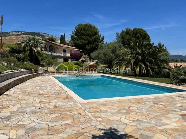 Découvrez cette propriété d’exception où élégance, volumes et douceur de vivre se rencontrent dans un cadre privilégié.

Édifiée sur un magnifique terrain de 3 939 m², cette villa de prestige développe près de 240 m² habitables, répartis entre une villa principale de plain-pied de 160 m² et une dépendance indépendante de 80 m². Un lieu pensé pour ceux qui recherchent espace, confort et sérénité, avec une vue dégagée remarquable sur les montagnes, la ville et la mer.

Dès l’entrée, la lumière s’invite naturellement grâce aux larges baies vitrées qui habillent le spacieux séjour et prolongent les espaces vers une terrasse généreuse et un jardin soigneusement aménagé. Son exposition Sud-Est sublime chaque instant de la journée.

Le salon s’ouvre harmonieusement sur une cuisine moderne, entièrement équipée et ouverte sur l’espace de vie.

L’espace nuit propose trois belles chambres, dont une superbe suite parentale avec dressing et salle de bain privative, complétées par une salle d’eau, deux WC, une buanderie ainsi qu’un bureau donnant accès au garage.

Au niveau inférieur, une dépendance indépendante de 80 m² offre de nombreuses possibilités : recevoir famille et amis, activité professionnelle ou investissement locatif. Elle se compose d’un vaste séjour avec cheminée et cuisine américaine, d’une suite parentale avec salle d’eau et rangements, ainsi que d’un accès à une cave et un espace extérieur de stockage.

Les extérieurs ont été pensés comme une véritable invitation à la détente : une grande piscine 12 x 6, un élégant pool house avec cuisine d’été, douche, WC et local technique, plusieurs espaces de repos, un terrain de pétanque et de vastes espaces verts.

Deux garages ainsi que de nombreux stationnements complètent ce bien rare.

Prestations supplémentaires : classement énergétique A, panneaux solaires, arrosage automatique, goutte-à-goutte, fosse septique, cuve à gaz, eau du Canal de Provence.

Un lieu où les réveils commencent avec une vue inspirante et où les journées semblent toujours avoir un parfum de vacances.

Un véritable havre de paix à découvrir sans tarder.