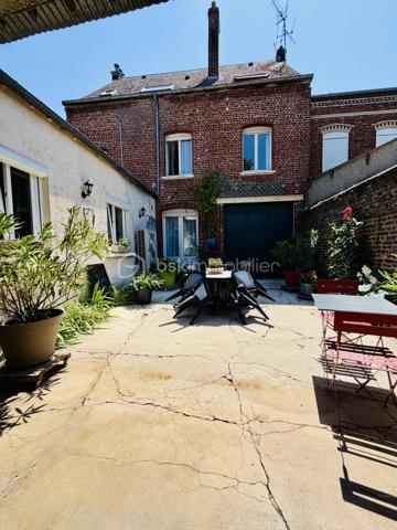Une maison pour ceux qui veulent une vraie adresse, une vraie façade, une vraie cour, de vraies chambres, et cette impression assez rare aujourd’hui : pouvoir accueillir large, vivre grand, et rester proche de tout.

On imagine très vite les grandes tablées, les enfants qui montent et descendent l’escalier, les courses que l’on décharge directement du garage à la cuisine, les repas dehors, les étés au calme, les chambres pleines et les dimanches qui s’étirent.

Rue Hoche, à Albert, cette maison individuelle d’environ 212 m² offre un équilibre rare : une vraie maison de ville, proche de tout, avec l’espace d’une grande maison familiale, une cour intime (80m2) tournée vers la rivière l’Ancre, un garage profond et 8 chambres ! 

Derrière sa façade en brique, solide et pleine de caractère, la maison dévoile des volumes généreux et une organisation pensée pour la vie quotidienne. Ici, on ne manque pas de place. Les pièces de réception permettent de recevoir, de dresser de grandes tables, de vivre ensemble sans se marcher dessus. La salle à manger et le salon conservent une atmosphère chaleureuse, avec de beaux détails, une cheminée, des rangements intégrés et cette âme que les maisons anciennes savent garder mieux que personne.

La cuisine est l’un des vrais cœurs de la maison. Spacieuse, conviviale, tournée vers la cour, elle offre aussi une vue rare et presque inattendue sur la Vierge de la Basilique. Un détail que l’on ne peut pas inventer, et que l’on apprécie chaque jour, sans même s’en rendre compte.

Côté pratique, le garage est un véritable atout. Profond, équipé d’une porte électrique, il permet d’accéder directement à la cour puis à la cuisine : les courses, les sacs, les vélos, les outils, tout devient plus simple. Un vrai confort de maison familiale, surtout en centre-ville.

À l’arrière, la cour change complètement l’ambiance. Calme, verdoyante, protégée des regards, elle donne sur la rivière l’Ancre. Sous la partie abritée, on accède à cet espace plus intime encore, avec établi, stockage et de nombreuses possibilités : atelier, cuisine d’été, coin bricolage, espace jacuzzi, salon extérieur couvert… chacun pourra y projeter son mode de vie.

La maison compte 8 chambres, ce qui ouvre de multiples usages : grande famille, famille recomposée, chambres d’amis, bureaux, espace ado, activité indépendante, hébergement ponctuel, location chambres meublées ou projet intergénérationnel. Chacun peut avoir sa place, et c’est suffisamment rare pour être souligné.

L’emplacement est un autre point fort. Rue Hoche, à Albert, les écoles sont accessibles à pied en environ 5 minutes, tout comme les commerces. On profite d’un quotidien simple, central, sans dépendre systématiquement de la voiture, tout en conservant les avantages d’une maison avec garage, cour et volumes.

Côté technique, la maison bénéficie d’un classement énergétique confortable pour une bâtisse ancienne : DPE C et GES A. Le chauffage est assuré principalement par une pompe à chaleur air/eau, avec insert bois en appoint. L’eau chaude est produite par un chauffe-eau thermodynamique complété par un ballon électrique. 
+ grande cave et grenier 
.
C’est une maison qui a de la place, du caractère, du pratique, du vivant.