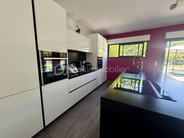 Située dans un cadre privilégié, en lot arrière, à l’abri des regards, cette remarquable maison contemporaine de 208 m² érigée en 2021 sur une parcelle de 951 m² vous offre un cadre de vie d’exception alliant confort absolu, prestations haut de gamme et tranquillité.

Toutes les commodités — écoles, commerces, transports — sont accessibles à moins de 10 minutes à pied, un atout rare qui conjugue vie au vert et praticité du quotidien.

LE REZ-DE-CHAUSSÉE:
Dès l’entrée, vous serez saisi par le volume exceptionnel du séjour triple baigné de lumière, de plus de 70 m², orienté Est-Ouest, ouvert sur le jardin et sa piscine. La cuisine américaine, entièrement aménagée et équipée, s’intègre avec élégance dans cet espace de vie généreux, idéal pour recevoir.

Le rez-de-chaussée comprend également :
	•	Une suite parentale de 28 m² avec dressing, salle de bains dotée d’une douche à l’italienne et d’une baignoire balnéo — un véritable espace bien-être privatif
	•	Un cellier
	•	Un WC suspendu indépendant
	•	Un double garage de 45 m² avec coin buanderie et mezzanine de 28 m² utiles, offrant un potentiel d’aménagement supplémentaire considérable

L’ÉTAGE:
L’étage est dédié au repos et à l’intimité de chacun. Il se compose de :
	•	3 suites de 28 m² chacune, toutes dotées d’un dressing et desservies par 1 salle de bains et 2 salles d’eau
	•	1 chambre d’amis de 15 m²
	•	Un WC suspendu indépendant

Une configuration idéale pour les familles nombreuses ou pour accueillir les proches dans les meilleures conditions.

LES EXTÉRIEURS:
L’extérieur est à la hauteur de l’intérieur. Une allée de 250 m² dessert la propriété et offre de nombreuses places de stationnement, complétées par des emplacements libres dans la rue.

Le terrain d’environ 700 m² accueille :
	•	Une terrasse de 40 m², parfaite pour les beaux jours
	•	Une piscine 8 x 3,5 m avec plage, chauffée par pompe à chaleur, équipée d’un volet électrique et d’un local technique dédié

LES ATOUTS TECHNIQUES:
Cette maison a été construite avec des matériaux de qualité supérieure et bénéficie de toutes les garanties :

	•	✅ Garantie décennale & dommages-ouvrage (construction 2021)
	•	✅ Construction en briques et escalier béton
	•	✅ Chauffage au sol par pompe à chaleur géothermique, complété par des radiateurs au gaz
	•	✅ Ballon thermodynamique
	•	✅ Norme RT 2012 — performance énergétique maîtrisée
	•	✅ 2 puisards pour une gestion optimale des eaux

Une propriété rare, clé en main, sans aucun travaux à prévoir. À visiter absolument.

Prix de vente : 800 000 €

Visite virtuelle disponible très prochainement ! 

Conseillère disponible 7j/7.
📞 Contactez-moi dès maintenant pour programmer votre visite.