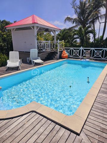Jérôme MIGLIORE vous propose pour BSK IMMOBILLIER /

PROPRIETE D'EXCEPTION - 7 PIECES - UNIQUE A LA VENTE A  SAINT- FRANCOIS :

Située sur les hauteurs de Saint-François, à proximité immédiate du golf, de la marina, du casino, des plages, ainsi que de tous commerces et restaurants, cette superbe villa bénéficie d’un emplacement idéal au sein d’un lotissement paisible, offrant un cadre de vie des plus agréables.

D’une superficie de 181 m² de surface habitable ( habitation et annexes), cette demeure aux volumes généreux se compose de :

Un vaste séjour traversant de 50 m², lumineux et parfaitement ventilé, s’ouvrant sur deux terrasses,
Quatre chambres spacieuses, dont deux avec salle d’eau privative/ WC et une avec salle de bains avec WC,
Une mezzanine, idéale pour un espace bureau, bibliothèque, chambre ou salle de jeux,
Une cuisine indépendante avec office, fonctionnelle et bien agencée,
Bureau,
Un WC visiteurs.

Espaces extérieurs et équipements:
L’extérieur, conçu pour le confort et la convivialité, vous invite à la détente :
Une terrasse couverte avec un carbet équipé d’un jacuzzi (stores pour préserver votre intimité),
Une piscine au sel avec son deck, parfaite pour des moments de farniente sous le soleil des tropiques,
Un espace cuisine et salon extérieur, avec bar et barbecue, idéal pour recevoir famille et amis,
Un jardin arboré et parfaitement entretenu sur un terrain plat de 1 400 m² environ, entièrement clôturé, sans aucun vis-à-vis.

Autres atouts:
Capacité de stationnement pour 5 véhicules + Grand garage fermé de 45 m²,
Deux entrées indépendantes avec portails motorisés,
Construction 100 % béton, assurant une parfaite résistance aux conditions cycloniques,
Toiture révisée et repeinte en 2024,
Réserve d’eau de 2 000 litres,
Chauffe-eau solaire,
DPE réalisé en janvier 2025 – Classe B.

Un bien aux multiples possibilités,
Cette villa d’exception peut convenir aussi bien en résidence principale qu’en investissement locatif, avec un fort potentiel pour une activité de maison d’hôtes ou de locations saisonnières. De plus, une ou deux constructions supplémentaires de type bungalow peuvent être envisagées sur le terrain. ( zone U4 du PLU)

Un véritable havre de paix où luxe, confort et sérénité se conjuguent à la perfection.

Pour plus d’informations
Des vidéos du bien sont disponibles sur demande.

Ne manquez pas cette opportunité unique ! Contactez moi rapidement .