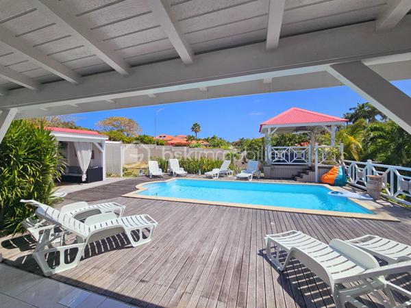 Jérôme MIGLIORE vous propose pour BSK IMMOBILLIER /

PROPRIETE D'EXCEPTION - 7 PIECES - UNIQUE A LA VENTE A  SAINT- FRANCOIS :

Située sur les hauteurs de Saint-François, à proximité immédiate du golf, de la marina, du casino, des plages, ainsi que de tous commerces et restaurants, cette superbe villa bénéficie d’un emplacement idéal au sein d’un lotissement paisible, offrant un cadre de vie des plus agréables.

D’une superficie de 181 m² de surface habitable ( habitation et annexes), cette demeure aux volumes généreux se compose de :

Un vaste séjour traversant de 50 m², lumineux et parfaitement ventilé, s’ouvrant sur deux terrasses,
Quatre chambres spacieuses, dont deux avec salle d’eau privative/ WC et une avec salle de bains avec WC,
Une mezzanine, idéale pour un espace bureau, bibliothèque, chambre ou salle de jeux,
Une cuisine indépendante avec office, fonctionnelle et bien agencée,
Bureau,
Un WC visiteurs.

Espaces extérieurs et équipements:
L’extérieur, conçu pour le confort et la convivialité, vous invite à la détente :
Une terrasse couverte avec un carbet équipé d’un jacuzzi (stores pour préserver votre intimité),
Une piscine au sel avec son deck, parfaite pour des moments de farniente sous le soleil des tropiques,
Un espace cuisine et salon extérieur, avec bar et barbecue, idéal pour recevoir famille et amis,
Un jardin arboré et parfaitement entretenu sur un terrain plat de 1 400 m² environ, entièrement clôturé, sans aucun vis-à-vis.

Autres atouts:
Capacité de stationnement pour 5 véhicules + Grand garage fermé de 45 m²,
Deux entrées indépendantes avec portails motorisés,
Construction 100 % béton, assurant une parfaite résistance aux conditions cycloniques,
Toiture révisée et repeinte en 2024,
Réserve d’eau de 2 000 litres,
Chauffe-eau solaire,
DPE réalisé en janvier 2025 – Classe B.

Un bien aux multiples possibilités,
Cette villa d’exception peut convenir aussi bien en résidence principale qu’en investissement locatif, avec un fort potentiel pour une activité de maison d’hôtes ou de locations saisonnières. De plus, une ou deux constructions supplémentaires de type bungalow peuvent être envisagées sur le terrain. ( zone U4 du PLU)

Un véritable havre de paix où luxe, confort et sérénité se conjuguent à la perfection.

Pour plus d’informations
Des vidéos du bien sont disponibles sur demande.

Ne manquez pas cette opportunité unique ! Contactez moi rapidement .