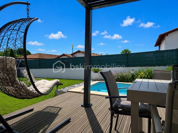 Maison contemporaine de plain-pied avec piscine – 4 chambres – Proche Bayonne

  Un véritable coup de cœur à découvrir sans tarder !

Dans un environnement calme et résidentiel, découvrez cette jolie maison contemporaine de 2017, 
entièrement de plain-pied, implantée sur une parcelle clôturée de 413 m².

Idéalement située, vous serez à seulement  5 minutes du centre commercial Ametzondo et 10 minutes de Bayonne.

    - VISITE VIRTUELLE SUR DEMANDE - GRATUITE

Dès l'entrée, vous serez séduits par une belle pièce de vie lumineuse de 43 m², chaleureuse et conviviale, 
agrémentée d'un poêle à granulés. 
Elle s'ouvre directement sur les extérieurs et la piscine.

La cuisine ouverte, aménagée et équipée, s'intègre parfaitement à cet espace de vie pensé pour profiter pleinement 
des moments en famille ou entre amis.

Un espace nuit confortable :

La maison propose 4 chambres, dont une belle **suite parentale** avec :

* dressing,
* salle d'eau avec douche à l'italienne,
* WC.

Un cellier avec accès au garage, une seconde salle d'eau et un WC indépendant viennent compléter l'espace intérieur.

Un extérieur pensé pour profiter pleinement des beaux jours.

Vous apprécierez particulièrement son jardin clos et facile à vivre, ainsi que ses deux terrasses exposées Sud-Ouest.

L'une bénéficie d'une pergola, l'autre d'un store, permettant de profiter des extérieurs à différents moments de la journée.

Et pour les journées ensoleillées : place à la détente avec une piscine chauffée et équipée d'une filtration au sel ! 

Un garage de 15 m² complète l'ensemble.

Les prestations : 

* Maison récente de 2017
* Plain-pied
* 4 chambres
* Piscine chauffée avec filtration au sel
* Poêle à granulés + chauffage électrique
* Eau chaude par ballon thermodynamique
* Huisseries PVC double vitrage
* Volets roulants électriques et bois
* VMC
* Moustiquaires
* Fibre
* Tout-à-l'égout
* Garage de 15 m²

  Les + qui font la différence :

Plain-pied • Maison récente • Excellent diagnostic performance énergétique classé en A et A • 4 chambres • Piscine • Jardin clos
• Terrasses • Calme • Proximité Bayonne

Une maison fonctionnelle, lumineuse et parfaitement adaptée à une vie de famille, où tout est réuni pour profiter 
d'un cadre de vie agréable à proximité immédiate de Bayonne.

Une maison coup de cœur qui ne devrait pas rester longtemps sur le marché… Alors, ne tardez pas !

 Je suis à votre écoute 7 jours sur 7 et m'adapte à votre planning pour organiser votre visite.