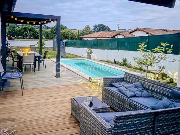 Maison contemporaine de plain-pied avec piscine – 4 chambres – Proche Bayonne

  Un véritable coup de cœur à découvrir sans tarder !

Dans un environnement calme et résidentiel, découvrez cette jolie maison contemporaine de 2017, 
entièrement de plain-pied, implantée sur une parcelle clôturée de 413 m².

Idéalement située, vous serez à seulement  5 minutes du centre commercial Ametzondo et 10 minutes de Bayonne.

    - VISITE VIRTUELLE SUR DEMANDE - GRATUITE

Dès l'entrée, vous serez séduits par une belle pièce de vie lumineuse de 43 m², chaleureuse et conviviale, 
agrémentée d'un poêle à granulés. 
Elle s'ouvre directement sur les extérieurs et la piscine.

La cuisine ouverte, aménagée et équipée, s'intègre parfaitement à cet espace de vie pensé pour profiter pleinement 
des moments en famille ou entre amis.

Un espace nuit confortable :

La maison propose 4 chambres, dont une belle **suite parentale** avec :

* dressing,
* salle d'eau avec douche à l'italienne,
* WC.

Un cellier avec accès au garage, une seconde salle d'eau et un WC indépendant viennent compléter l'espace intérieur.

Un extérieur pensé pour profiter pleinement des beaux jours.

Vous apprécierez particulièrement son jardin clos et facile à vivre, ainsi que ses deux terrasses exposées Sud-Ouest.

L'une bénéficie d'une pergola, l'autre d'un store, permettant de profiter des extérieurs à différents moments de la journée.

Et pour les journées ensoleillées : place à la détente avec une piscine chauffée et équipée d'une filtration au sel ! 

Un garage de 15 m² complète l'ensemble.

Les prestations : 

* Maison récente de 2017
* Plain-pied
* 4 chambres
* Piscine chauffée avec filtration au sel
* Poêle à granulés + chauffage électrique
* Eau chaude par ballon thermodynamique
* Huisseries PVC double vitrage
* Volets roulants électriques et bois
* VMC
* Moustiquaires
* Fibre
* Tout-à-l'égout
* Garage de 15 m²

  Les + qui font la différence :

Plain-pied • Maison récente • Excellent diagnostic performance énergétique classé en A et A • 4 chambres • Piscine • Jardin clos
• Terrasses • Calme • Proximité Bayonne

Une maison fonctionnelle, lumineuse et parfaitement adaptée à une vie de famille, où tout est réuni pour profiter 
d'un cadre de vie agréable à proximité immédiate de Bayonne.

Une maison coup de cœur qui ne devrait pas rester longtemps sur le marché… Alors, ne tardez pas !

 Je suis à votre écoute 7 jours sur 7 et m'adapte à votre planning pour organiser votre visite.