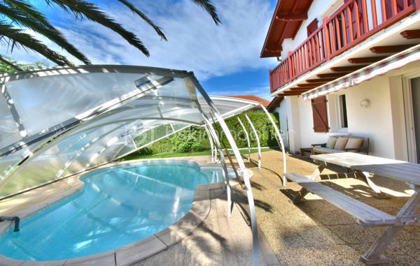 A 200 mètres à pied de la place du village et des plages, cette maison néo-basque bénéficie d'un emplacement que l'on trouve très rarement à Bidart : central, au calme et côté océan.
Développant environ 215 m2 sur un terrain de 1000 m2, la maison offre aujourd'hui 5 chambres, 2 salles de bain, une cuisine indépendante avec arrière cuisine et un séjour lumineux ouvert sur l'extérieur. La terrasse plein Sud avec piscine prolonge naturellement les espaces de vie et permet de profiter pleinement du cadre. Garage, atelier et abri de piscine complètent l'ensemble. La maison est parfaitement entretenue, mais nécessite une remise au goût du jour. Le potentiel est évident pour qui souhaite créer un lieu de vie à la hauteur de l'adresse. Ici, la vraie valeur n'est pas seulement dans la maison, mais dans ce qu'elle permet : vivre Bidart à pied, entre village et océan, dans un environnement préservé. Ce type de bien ne se juge pas sur ses photos. Il se découvre sur place. Visite sur rendez-vous.