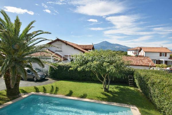 A 200 mètres à pied de la place du village et des plages, cette maison néo-basque bénéficie d'un emplacement que l'on trouve très rarement à Bidart : central, au calme et côté océan.
Développant environ 215 m2 sur un terrain de 1000 m2, la maison offre aujourd'hui 5 chambres, 2 salles de bain, une cuisine indépendante avec arrière cuisine et un séjour lumineux ouvert sur l'extérieur. La terrasse plein Sud avec piscine prolonge naturellement les espaces de vie et permet de profiter pleinement du cadre. Garage, atelier et abri de piscine complètent l'ensemble. La maison est parfaitement entretenue, mais nécessite une remise au goût du jour. Le potentiel est évident pour qui souhaite créer un lieu de vie à la hauteur de l'adresse. Ici, la vraie valeur n'est pas seulement dans la maison, mais dans ce qu'elle permet : vivre Bidart à pied, entre village et océan, dans un environnement préservé. Ce type de bien ne se juge pas sur ses photos. Il se découvre sur place. Visite sur rendez-vous.