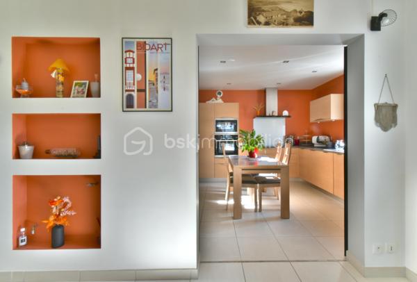 A 200 mètres à pied de la place du village et des plages, cette maison néo-basque bénéficie d'un emplacement que l'on trouve très rarement à Bidart : central, au calme et côté océan.
Développant environ 215 m2 sur un terrain de 1000 m2, la maison offre aujourd'hui 5 chambres, 2 salles de bain, une cuisine indépendante avec arrière cuisine et un séjour lumineux ouvert sur l'extérieur. La terrasse plein Sud avec piscine prolonge naturellement les espaces de vie et permet de profiter pleinement du cadre. Garage, atelier et abri de piscine complètent l'ensemble. La maison est parfaitement entretenue, mais nécessite une remise au goût du jour. Le potentiel est évident pour qui souhaite créer un lieu de vie à la hauteur de l'adresse. Ici, la vraie valeur n'est pas seulement dans la maison, mais dans ce qu'elle permet : vivre Bidart à pied, entre village et océan, dans un environnement préservé. Ce type de bien ne se juge pas sur ses photos. Il se découvre sur place. Visite sur rendez-vous.