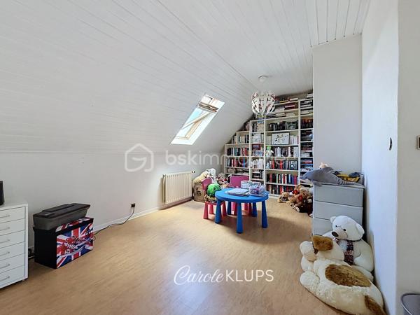Maison familiale avec véranda, terrasse couverte, jardin et piscine à Village-Neuf

Ici, la surface habitable ne raconte pas tout. 112 m² habitables auxquels s’ajoutent une véranda d’environ 10 m², une terrasse couverte tournée vers le jardin, un sous-sol et un double garage. 

Le charme d’une maison des années 30 dans laquelle on peut se créer une véritable vie dedans-dehors, à deux pas de la frontière bâloise. Et pour les frontaliers, Bâle est accessible à vélo via la piste cyclable longeant le canal de Huningue.

Depuis la rue, on ne soupçonne pas le cadre de vie que cette maison réserve à l’arrière.

Résolument tournée vers l’extérieur, elle s’ouvre sur un jardin intimiste où chaque espace trouve naturellement sa place. Une belle terrasse couverte pour les repas entre amis ou en famille. À moins que vous ne préfériez vous installer au bord de la piscine chauffée … Autour, l’espace paysager invite au repos et à la convivialité.

Une sensation de vacances chez soi, avec un autre avantage appréciable : un jardin aux dimensions raisonnables, pensé pour en profiter sans devenir esclave de son entretien. Un puits présent sur la propriété permet par ailleurs d’assurer l’arrosage du jardin.

À l’intérieur aussi, chaque espace a sa fonction et la circulation est fluide.

Au rez-de-chaussée, le séjour de 32,6 m² invite à se prélasser près du poêle à bois. La cuisine équipée de 12 m² offre un espace confortable pour cuisiner, tandis que la véranda d’environ 10 m² devient naturellement une pièce supplémentaire pour partager les repas, avec le jardin en toile de fond.

Le + de ce rez-de-chaussée ? Une salle d’eau avec WC.

En montant à l’étage, même le palier a été optimisé avec un petit espace buanderie astucieusement dissimulé.

Puis vient l’une des belles surprises de la maison : une vaste mezzanine de plus de 23 m².

Aujourd’hui ouverte, elle sera votre terrain de jeu. Espace télétravail, bibliothèque, salle de jeux pour les enfants, salon télé… à chacun d’imaginer sa façon de l’habiter. Elle pourra également être cloisonnée pour créer une troisième chambre, qui viendra alors compléter les deux chambres existantes de 12,6 et 11,2 m².

La salle de bains de 7,6 m², avec baignoire, double vasque et WC, est quant à elle dimensionnée pour ces matins en famille où l’on apprécie de ne pas se marcher dessus.

Et ce n’est pas tout.

Au sous-sol, on retrouve une partie chaufferie, un atelier ainsi qu’un espace déjà aménagé en salle de sport, à conserver tel quel ou à réinventer selon vos besoins.

À l’extérieur, le double garage, la piscine chauffée et son local technique indépendant complètent les prestations de la maison.

Le tout prend place sur une parcelle de 480 m².

Enfin, sa situation en zone frontalière, avec des accès faciles vers la Suisse comme vers l’Allemagne, est particulièrement adaptée à la vie quotidienne des actifs du secteur.

Une maison avec jardin et piscine, une vraie vie dedans-dehors et Bâle à portée de vélo : profiter pleinement de chez soi sans renoncer à la proximité de la frontière.