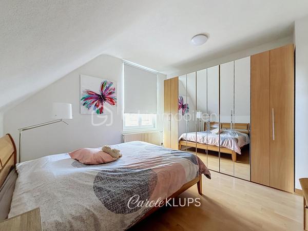 Maison familiale avec véranda, terrasse couverte, jardin et piscine à Village-Neuf

Ici, la surface habitable ne raconte pas tout. 112 m² habitables auxquels s’ajoutent une véranda d’environ 10 m², une terrasse couverte tournée vers le jardin, un sous-sol et un double garage. 

Le charme d’une maison des années 30 dans laquelle on peut se créer une véritable vie dedans-dehors, à deux pas de la frontière bâloise. Et pour les frontaliers, Bâle est accessible à vélo via la piste cyclable longeant le canal de Huningue.

Depuis la rue, on ne soupçonne pas le cadre de vie que cette maison réserve à l’arrière.

Résolument tournée vers l’extérieur, elle s’ouvre sur un jardin intimiste où chaque espace trouve naturellement sa place. Une belle terrasse couverte pour les repas entre amis ou en famille. À moins que vous ne préfériez vous installer au bord de la piscine chauffée … Autour, l’espace paysager invite au repos et à la convivialité.

Une sensation de vacances chez soi, avec un autre avantage appréciable : un jardin aux dimensions raisonnables, pensé pour en profiter sans devenir esclave de son entretien. Un puits présent sur la propriété permet par ailleurs d’assurer l’arrosage du jardin.

À l’intérieur aussi, chaque espace a sa fonction et la circulation est fluide.

Au rez-de-chaussée, le séjour de 32,6 m² invite à se prélasser près du poêle à bois. La cuisine équipée de 12 m² offre un espace confortable pour cuisiner, tandis que la véranda d’environ 10 m² devient naturellement une pièce supplémentaire pour partager les repas, avec le jardin en toile de fond.

Le + de ce rez-de-chaussée ? Une salle d’eau avec WC.

En montant à l’étage, même le palier a été optimisé avec un petit espace buanderie astucieusement dissimulé.

Puis vient l’une des belles surprises de la maison : une vaste mezzanine de plus de 23 m².

Aujourd’hui ouverte, elle sera votre terrain de jeu. Espace télétravail, bibliothèque, salle de jeux pour les enfants, salon télé… à chacun d’imaginer sa façon de l’habiter. Elle pourra également être cloisonnée pour créer une troisième chambre, qui viendra alors compléter les deux chambres existantes de 12,6 et 11,2 m².

La salle de bains de 7,6 m², avec baignoire, double vasque et WC, est quant à elle dimensionnée pour ces matins en famille où l’on apprécie de ne pas se marcher dessus.

Et ce n’est pas tout.

Au sous-sol, on retrouve une partie chaufferie, un atelier ainsi qu’un espace déjà aménagé en salle de sport, à conserver tel quel ou à réinventer selon vos besoins.

À l’extérieur, le double garage, la piscine chauffée et son local technique indépendant complètent les prestations de la maison.

Le tout prend place sur une parcelle de 480 m².

Enfin, sa situation en zone frontalière, avec des accès faciles vers la Suisse comme vers l’Allemagne, est particulièrement adaptée à la vie quotidienne des actifs du secteur.

Une maison avec jardin et piscine, une vraie vie dedans-dehors et Bâle à portée de vélo : profiter pleinement de chez soi sans renoncer à la proximité de la frontière.