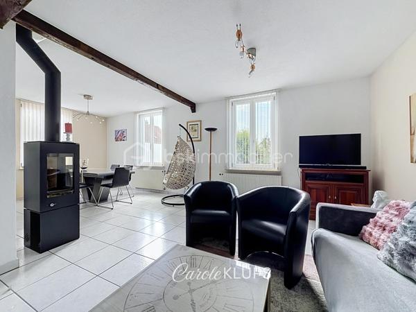 Maison familiale avec véranda, terrasse couverte, jardin et piscine à Village-Neuf

Ici, la surface habitable ne raconte pas tout. 112 m² habitables auxquels s’ajoutent une véranda d’environ 10 m², une terrasse couverte tournée vers le jardin, un sous-sol et un double garage. 

Le charme d’une maison des années 30 dans laquelle on peut se créer une véritable vie dedans-dehors, à deux pas de la frontière bâloise. Et pour les frontaliers, Bâle est accessible à vélo via la piste cyclable longeant le canal de Huningue.

Depuis la rue, on ne soupçonne pas le cadre de vie que cette maison réserve à l’arrière.

Résolument tournée vers l’extérieur, elle s’ouvre sur un jardin intimiste où chaque espace trouve naturellement sa place. Une belle terrasse couverte pour les repas entre amis ou en famille. À moins que vous ne préfériez vous installer au bord de la piscine chauffée … Autour, l’espace paysager invite au repos et à la convivialité.

Une sensation de vacances chez soi, avec un autre avantage appréciable : un jardin aux dimensions raisonnables, pensé pour en profiter sans devenir esclave de son entretien. Un puits présent sur la propriété permet par ailleurs d’assurer l’arrosage du jardin.

À l’intérieur aussi, chaque espace a sa fonction et la circulation est fluide.

Au rez-de-chaussée, le séjour de 32,6 m² invite à se prélasser près du poêle à bois. La cuisine équipée de 12 m² offre un espace confortable pour cuisiner, tandis que la véranda d’environ 10 m² devient naturellement une pièce supplémentaire pour partager les repas, avec le jardin en toile de fond.

Le + de ce rez-de-chaussée ? Une salle d’eau avec WC.

En montant à l’étage, même le palier a été optimisé avec un petit espace buanderie astucieusement dissimulé.

Puis vient l’une des belles surprises de la maison : une vaste mezzanine de plus de 23 m².

Aujourd’hui ouverte, elle sera votre terrain de jeu. Espace télétravail, bibliothèque, salle de jeux pour les enfants, salon télé… à chacun d’imaginer sa façon de l’habiter. Elle pourra également être cloisonnée pour créer une troisième chambre, qui viendra alors compléter les deux chambres existantes de 12,6 et 11,2 m².

La salle de bains de 7,6 m², avec baignoire, double vasque et WC, est quant à elle dimensionnée pour ces matins en famille où l’on apprécie de ne pas se marcher dessus.

Et ce n’est pas tout.

Au sous-sol, on retrouve une partie chaufferie, un atelier ainsi qu’un espace déjà aménagé en salle de sport, à conserver tel quel ou à réinventer selon vos besoins.

À l’extérieur, le double garage, la piscine chauffée et son local technique indépendant complètent les prestations de la maison.

Le tout prend place sur une parcelle de 480 m².

Enfin, sa situation en zone frontalière, avec des accès faciles vers la Suisse comme vers l’Allemagne, est particulièrement adaptée à la vie quotidienne des actifs du secteur.

Une maison avec jardin et piscine, une vraie vie dedans-dehors et Bâle à portée de vélo : profiter pleinement de chez soi sans renoncer à la proximité de la frontière.